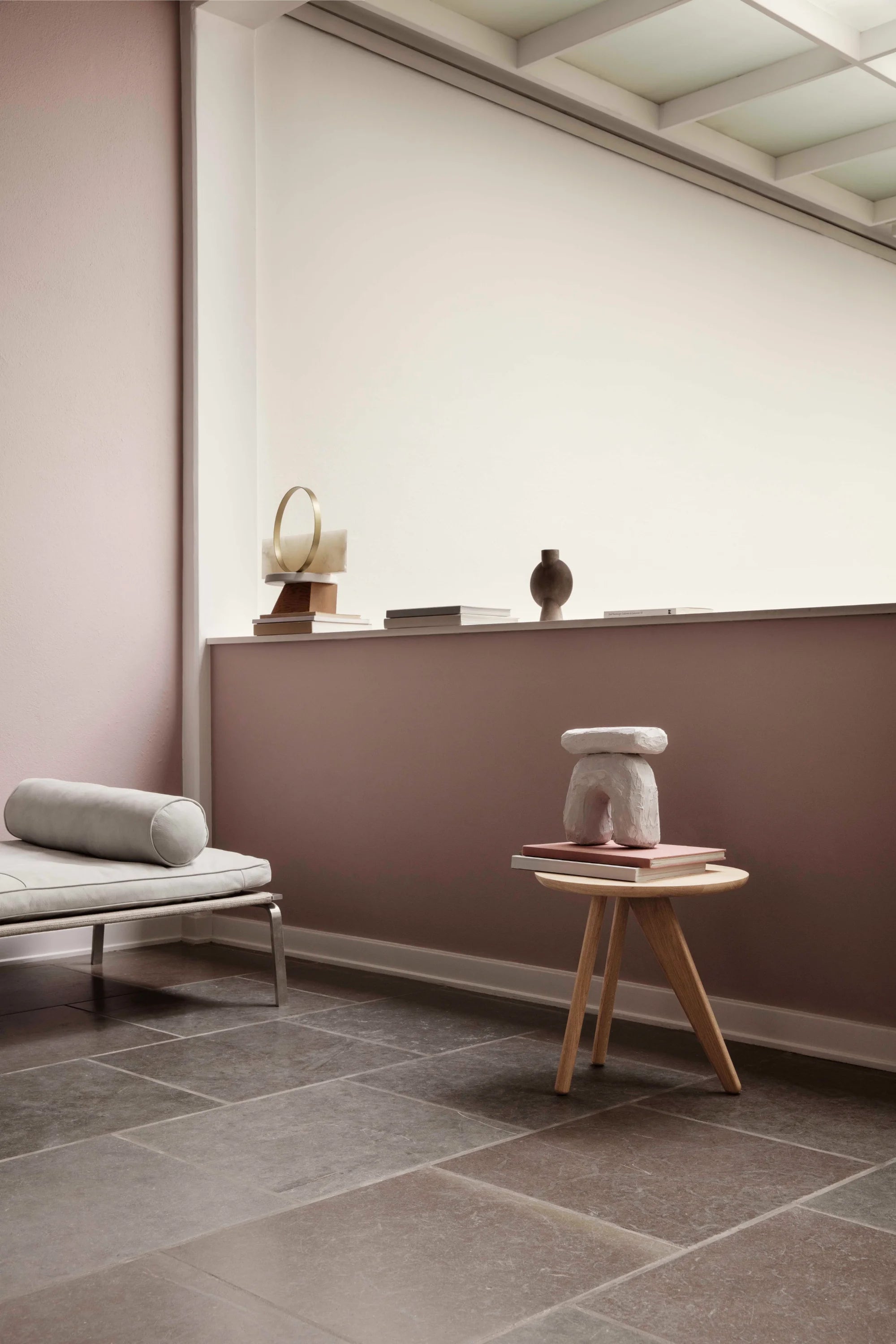 Modern interior with a small table, cushion, and decorative items against a wall.
