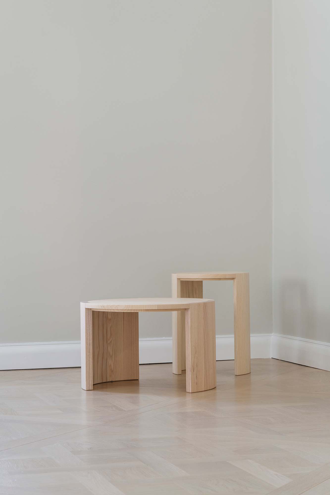Wooden stool and coffee table on a light wood floor against a plain wall.