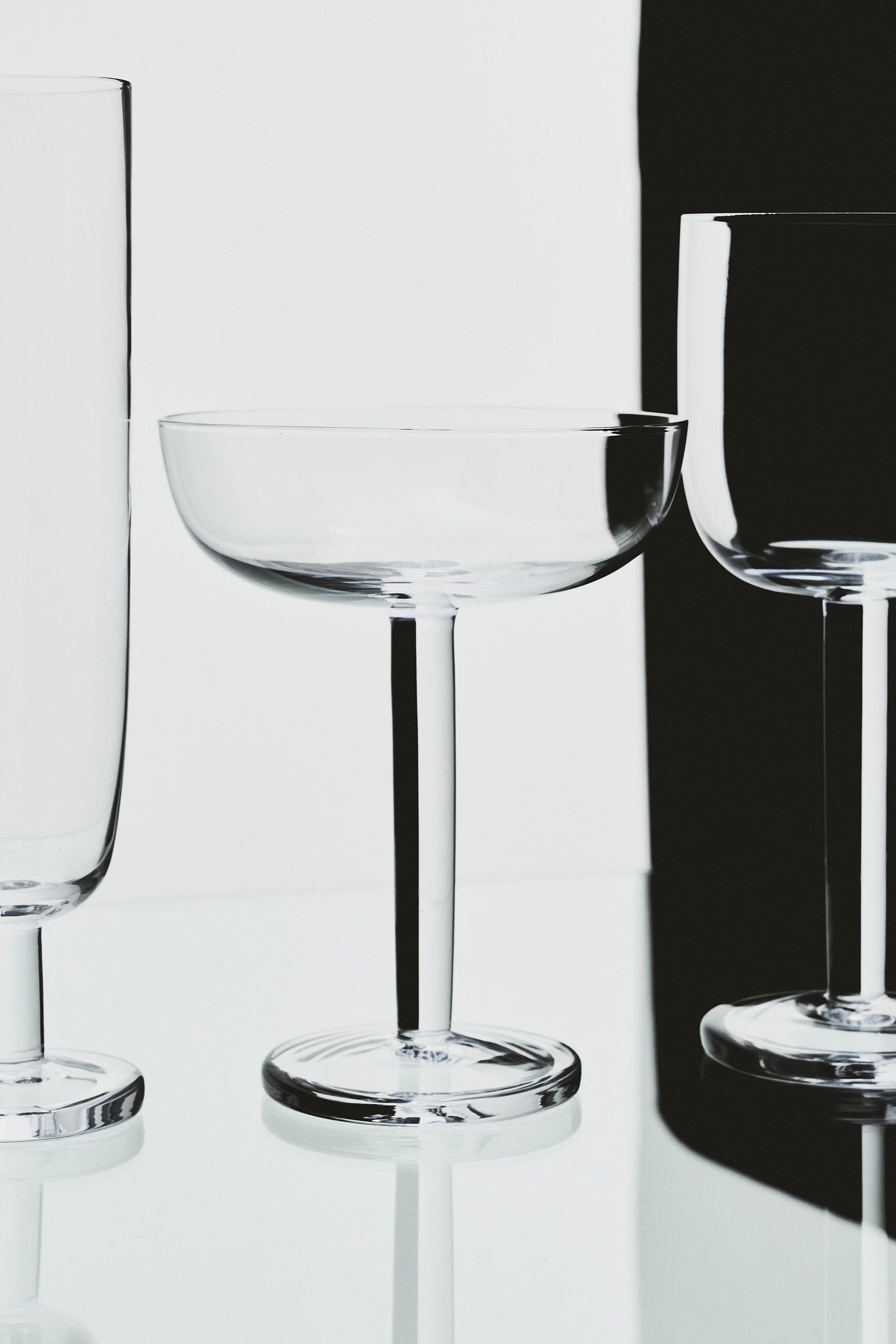 Three clear glassware items on a reflective surface with a black background