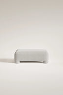 Gray upholstered ottoman on a light beige background