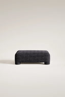 Dark gray textured ottoman on a light beige background