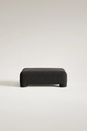 Black textured ottoman on a light gray background