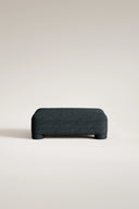 Dark gray upholstered bench on a light beige background