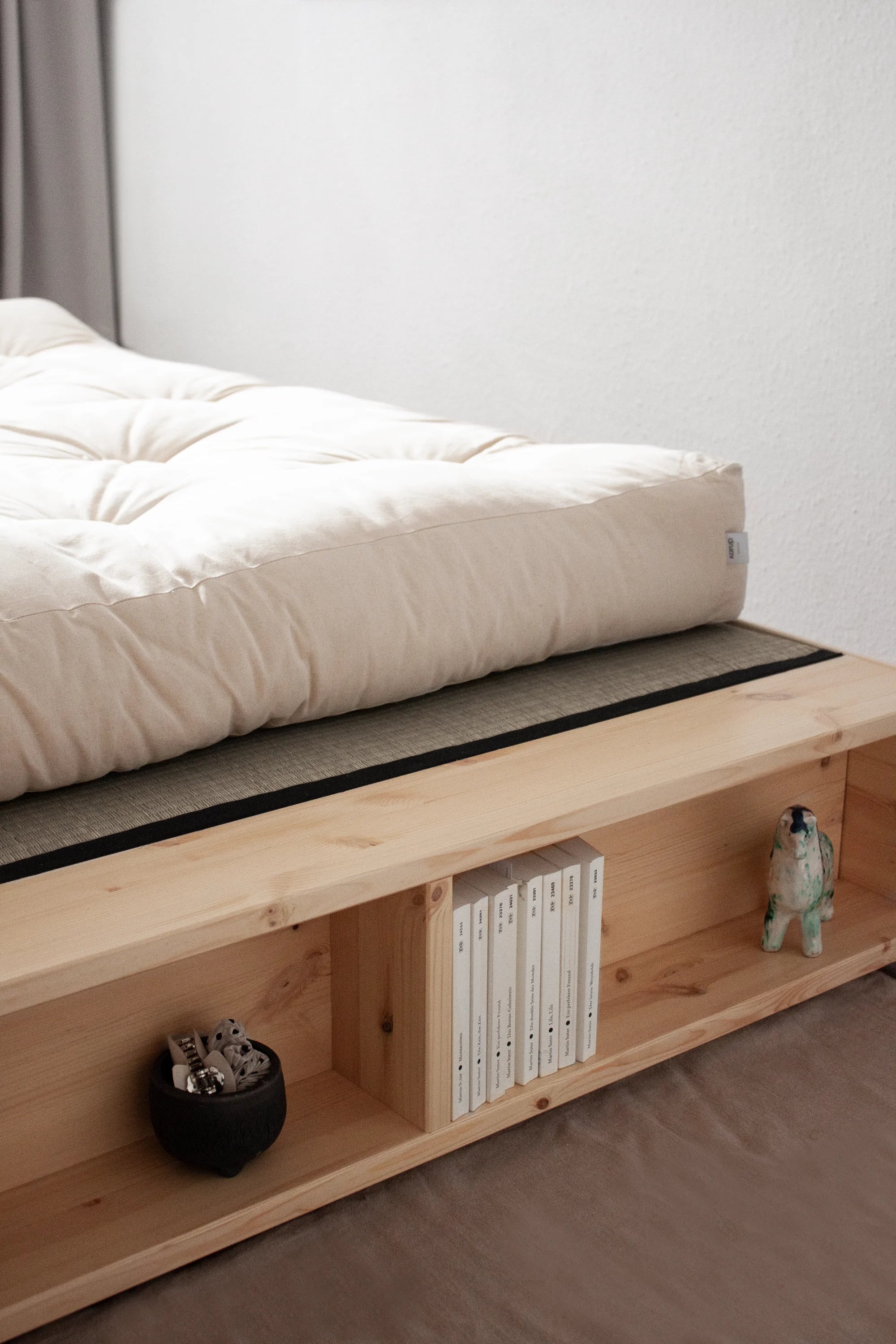 Wooden platform bed with storage shelves and a mattress on a plain background