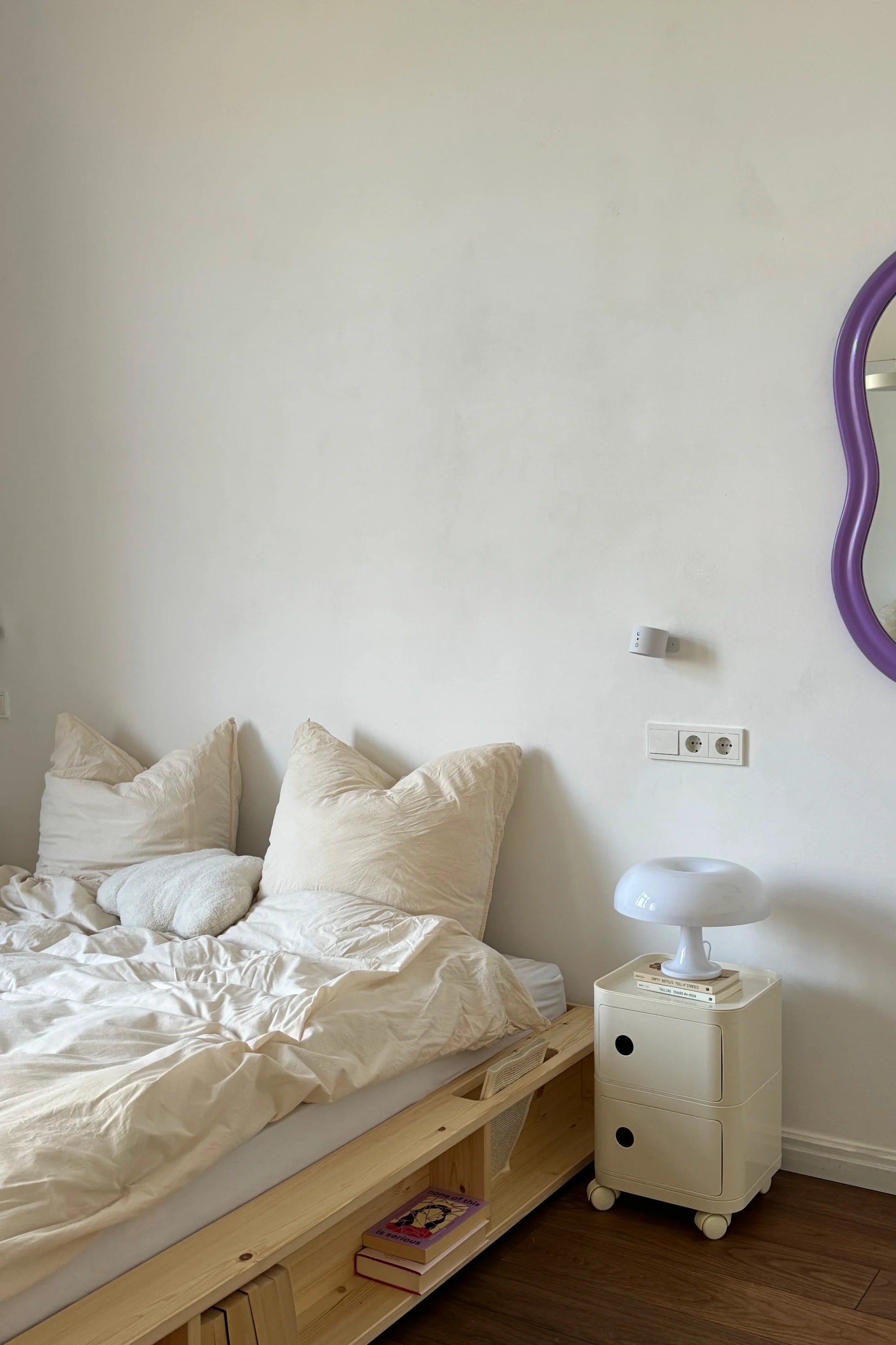 Bedroom with wooden bed, white pillows, and a nightstand with a lamp.