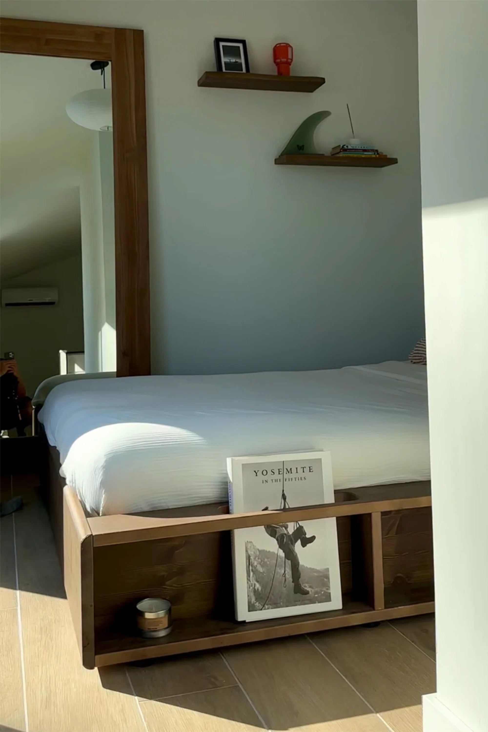 Bedroom with wooden bed frame, shelves, and decor items.