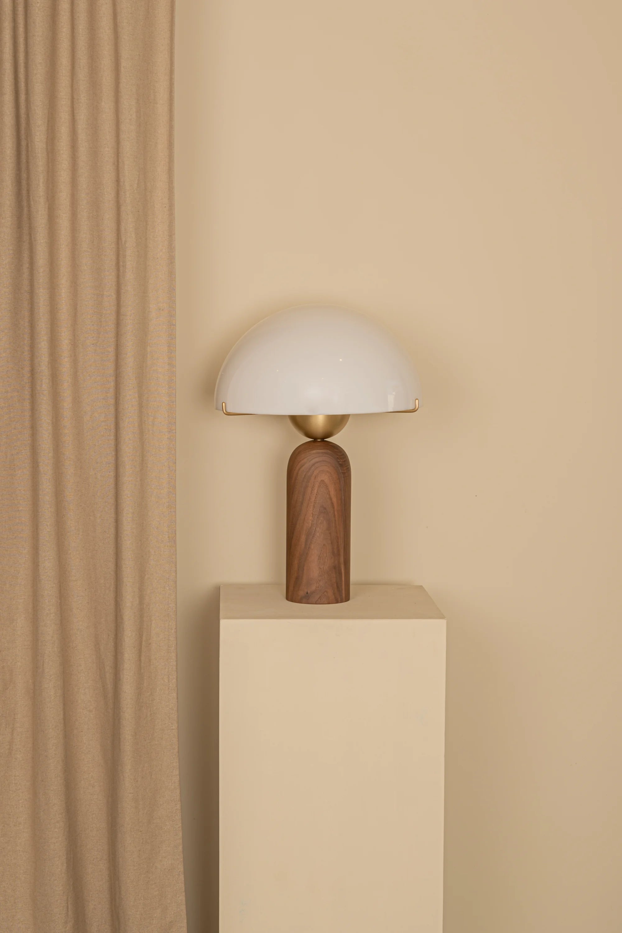 Table lamp with wooden base and white shade against a beige wall
