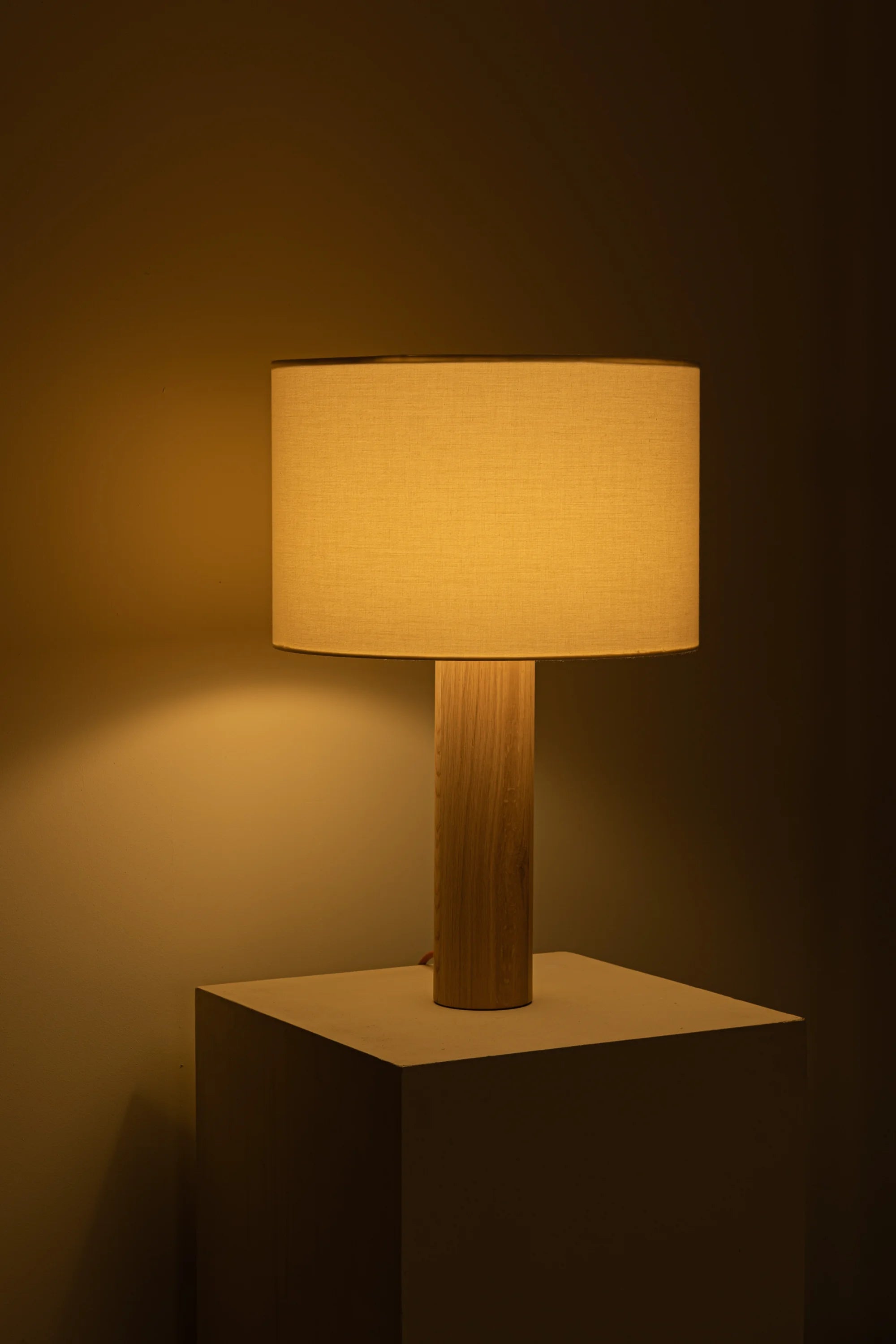 Table lamp with wooden base and beige shade on a dark background