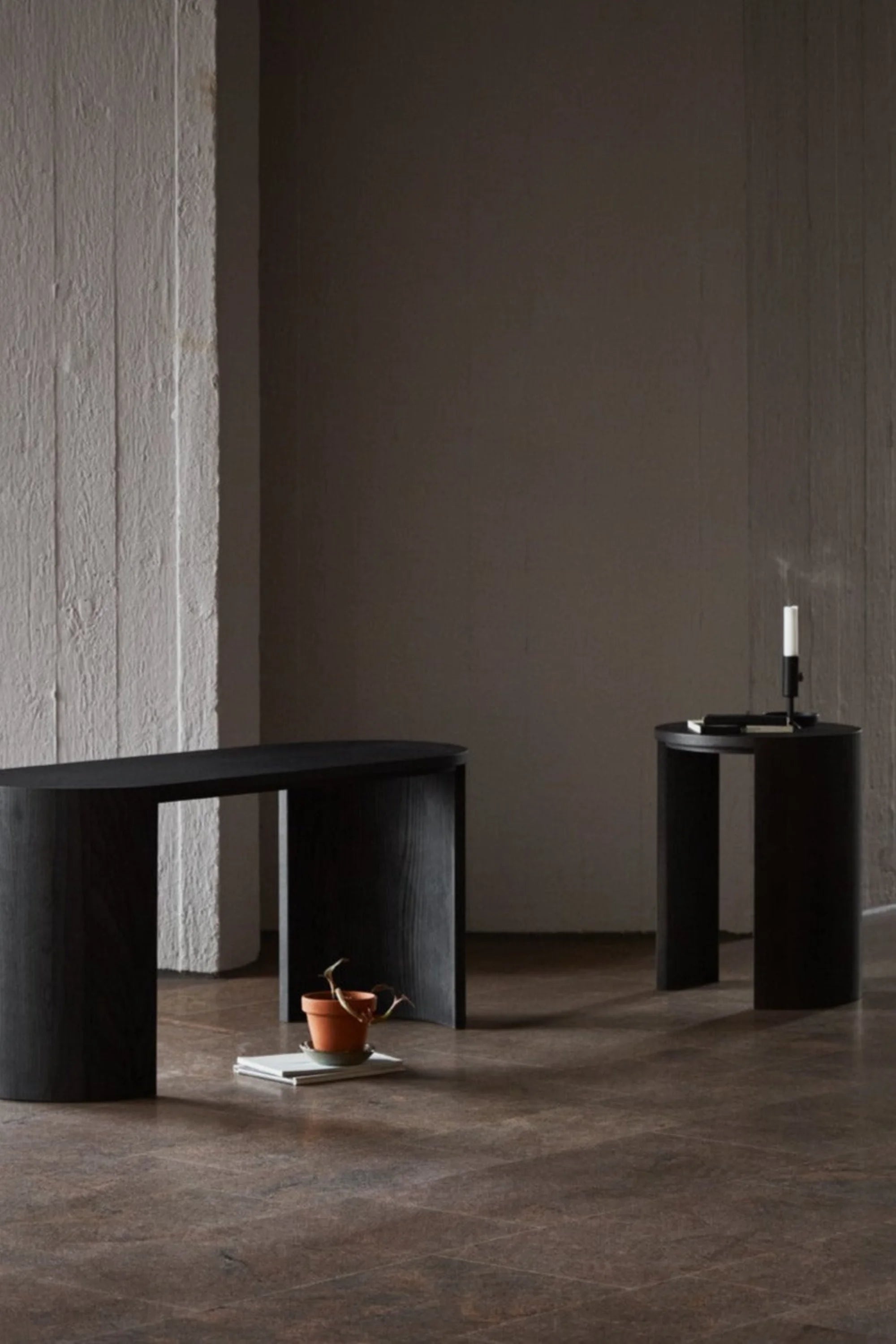 Two black side tables in a minimalistic room with a dark wall and floor.