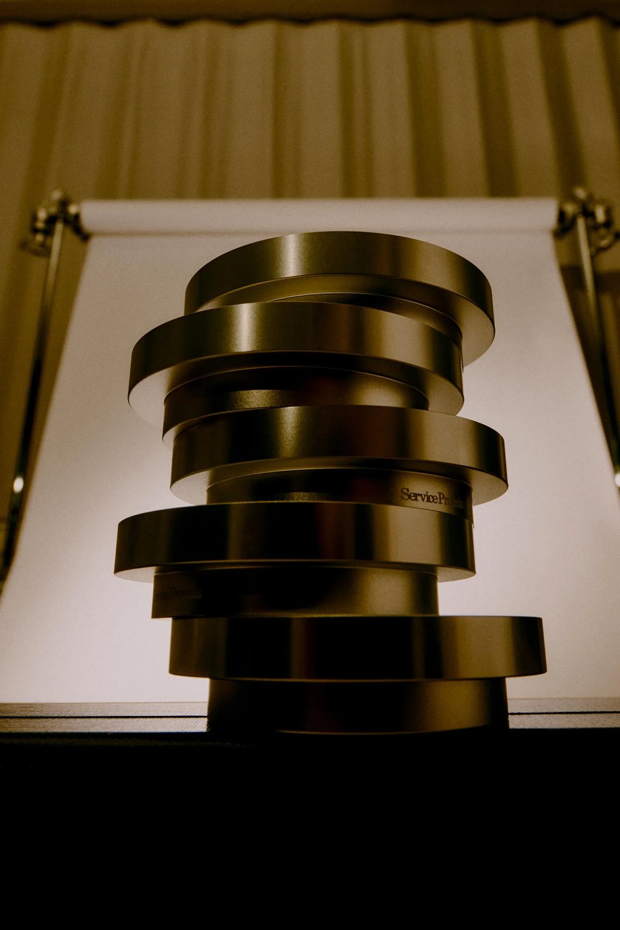 Stack of metallic egg cups on a reflective surface with a neutral background