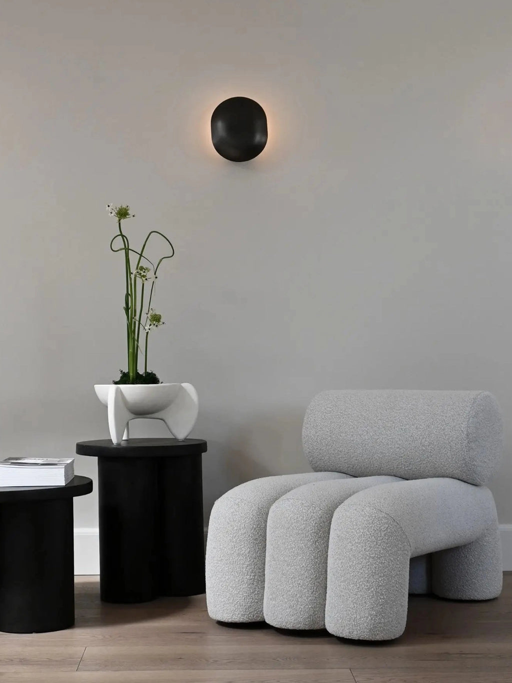 101 CPH Foku Lounge Chair in light grey textured bouclé fabric, featuring a unique, modern curved shape with distinct cylindrical legs and backrest. This premium minimalist seating is ideal for contemporary living spaces.