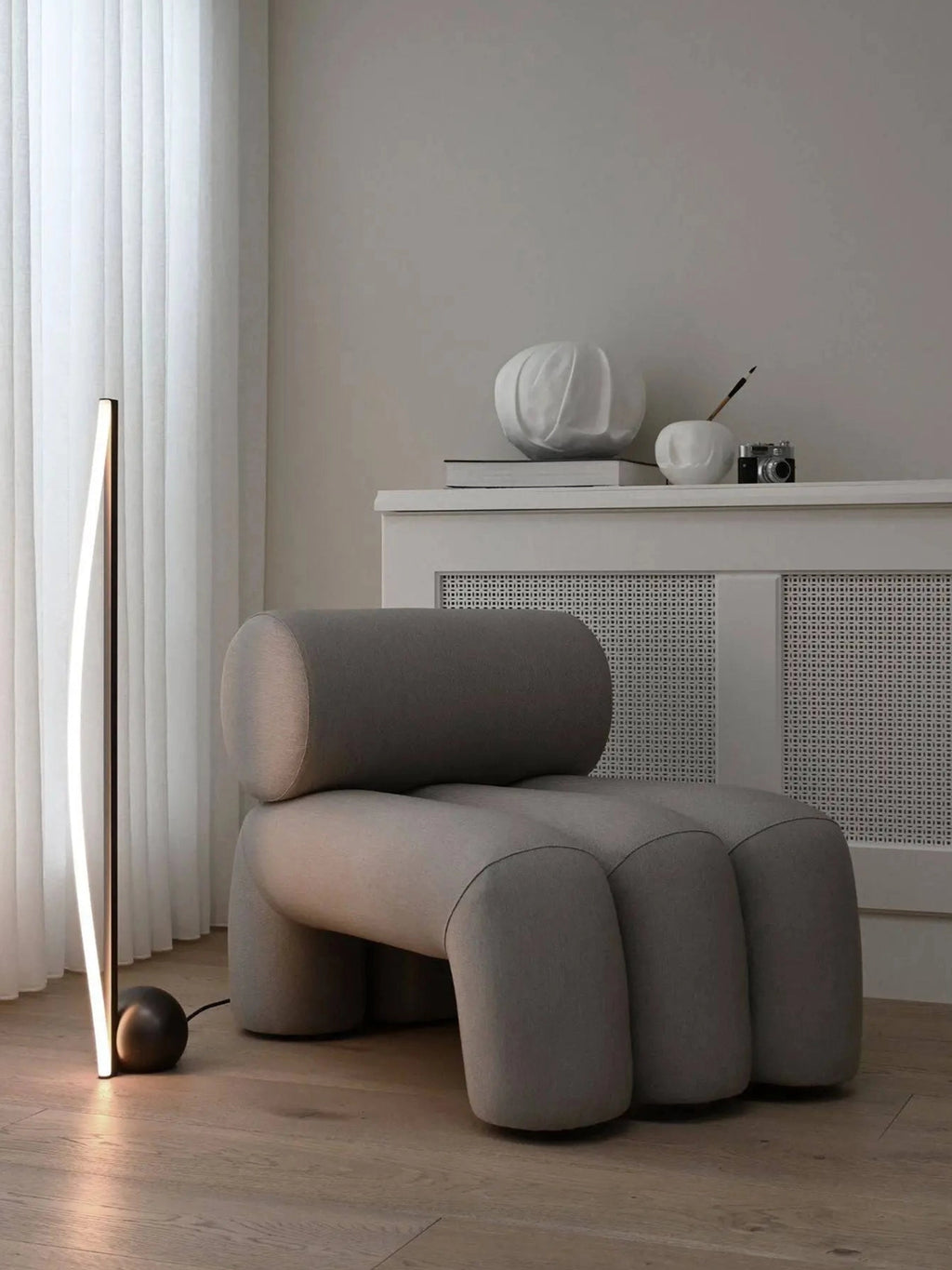 101 CPH Foku Lounge Chair in a modern light grey fabric, featuring a unique, plush, rounded cylindrical backrest and distinctive paw-like legs in a cozy living space. This authentic design promises premium comfort.