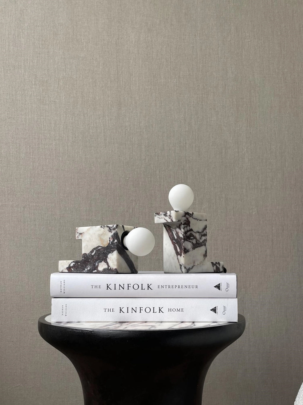 101 CPH Brick Lamp: Two luxury abstract lamps on a stack of books, crafted from white marble with deep purple-black veining, featuring spherical white bulbs. Ideal for sophisticated interior decor.