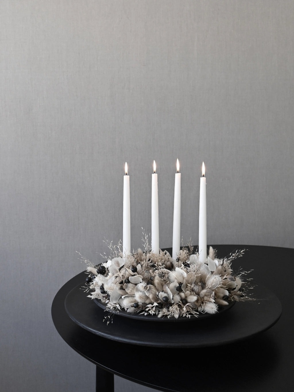 101 CPH Duck Tray in matte black ceramic, styled with a sophisticated dried floral arrangement holding four lit white taper candles, creating an elegant ambiance. Ideal for modern minimalist decor.