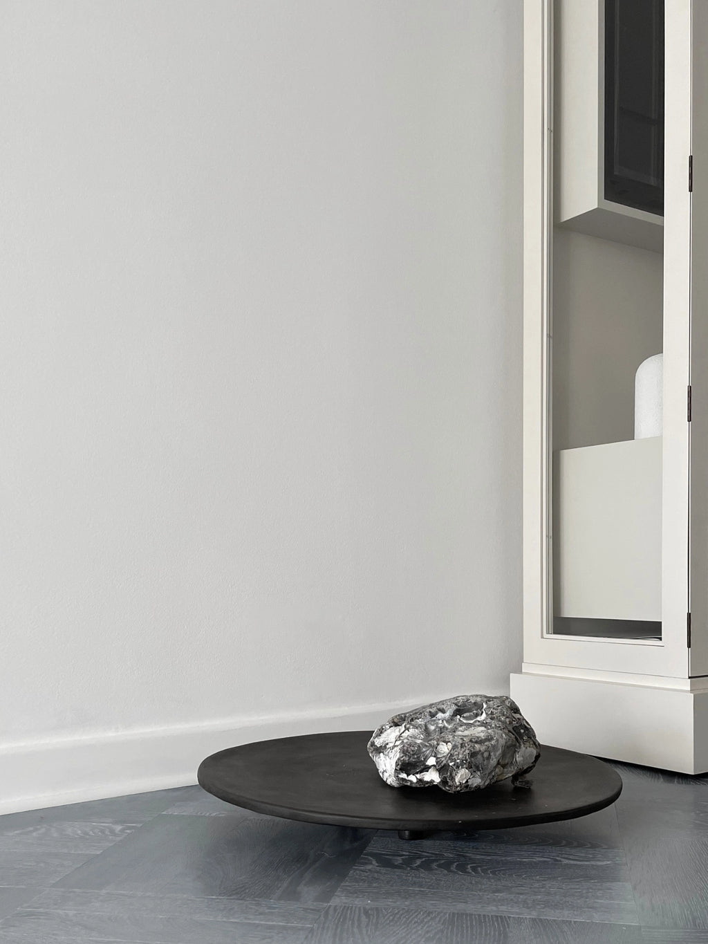 101 CPH Duck Tray; a dark grey, subtly textured round base with three small feet, holding a unique, grey-and-white mottled stone. A premium decorative piece for modern interior styling.