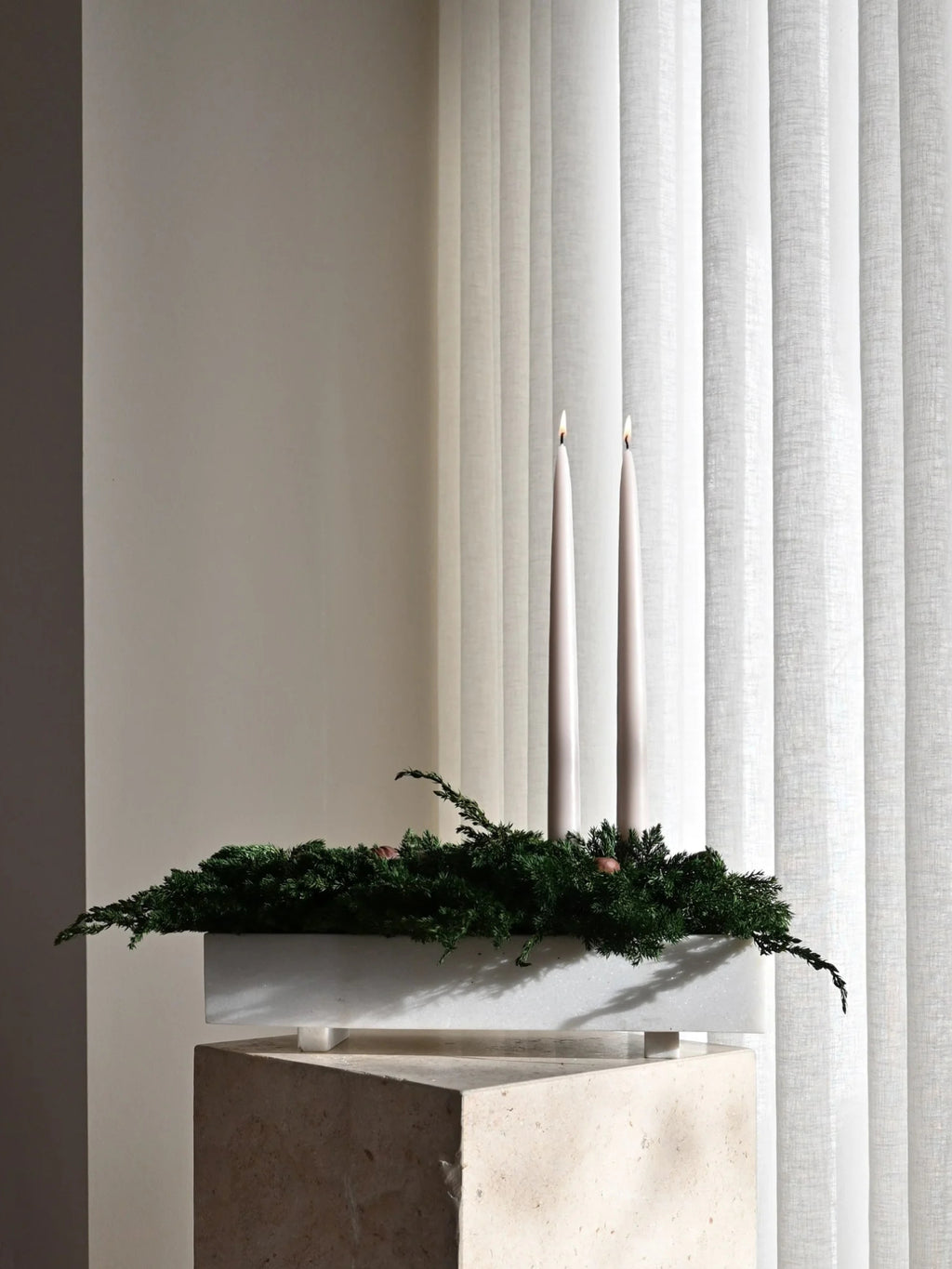 101 CPH Formalism Tray, a rectangular, premium white speckled terrazzo tray on short legs, filled with dark green foliage and two lit ivory taper candles, displayed on a textured beige block. Ideal for elegant home decor.
