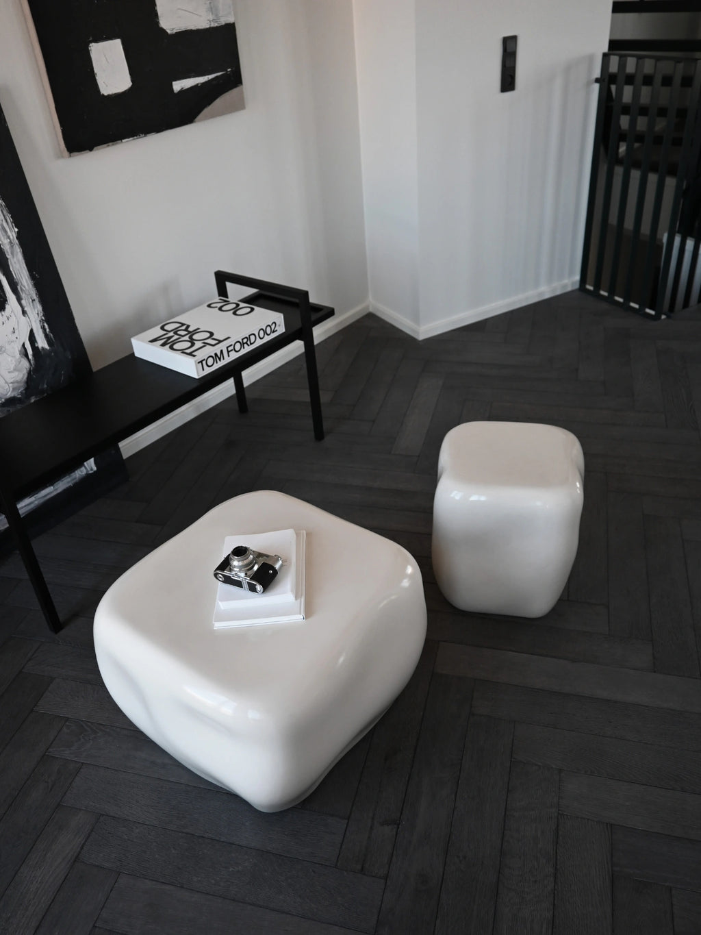 101 CPH Ishi Coffee Table Set - Ceramic, a luxurious white organic-shaped ceramic coffee table and matching cube-shaped side table on dark wood herringbone flooring. Ideal for modern living rooms.
