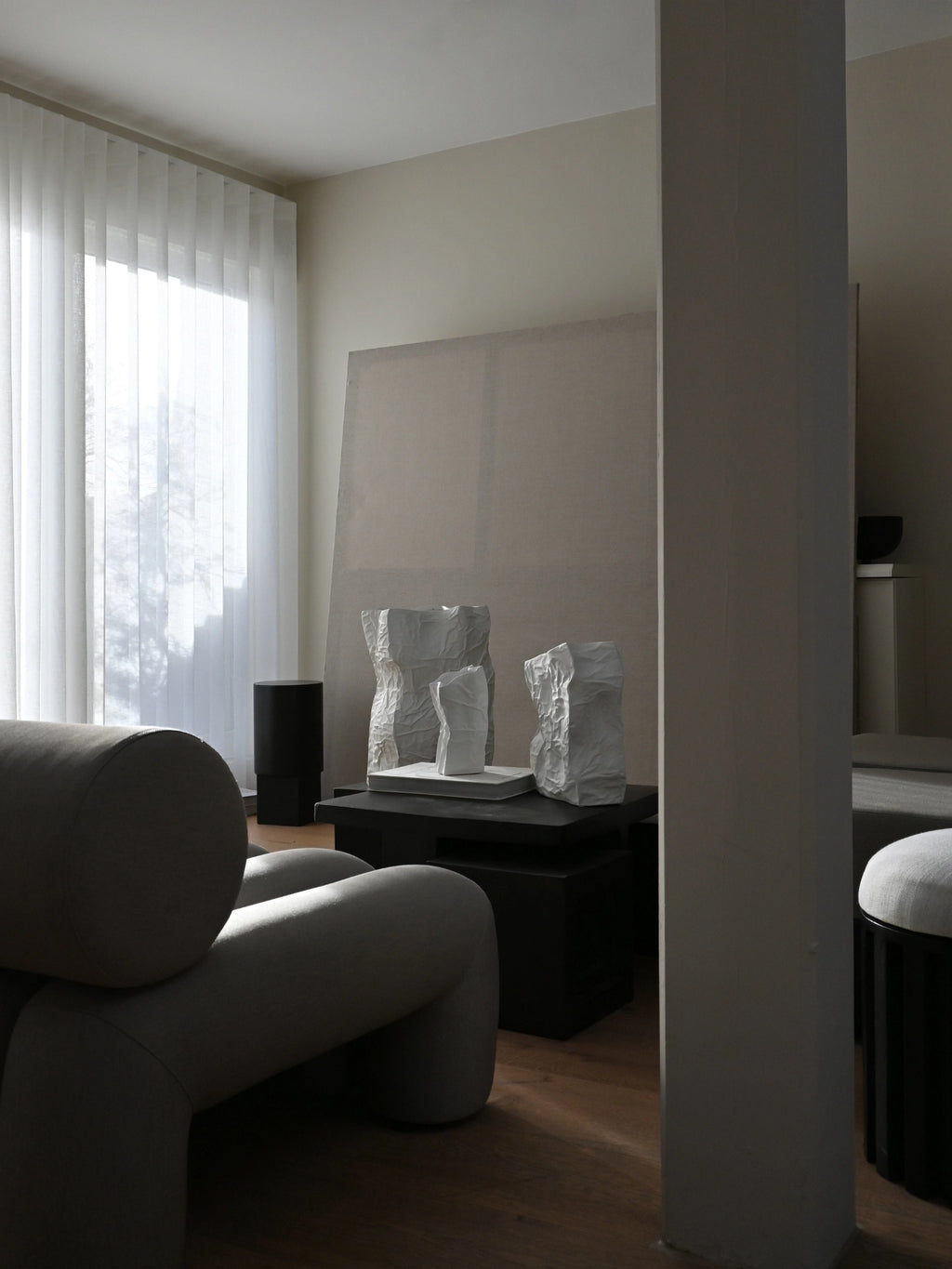 101 CPH Kami Vase collection: Three unique, handcrafted off-white ceramic vases with paper-like crumpled textures, styled on a dark coffee table in a modern living room. Perfect for contemporary interiors.
