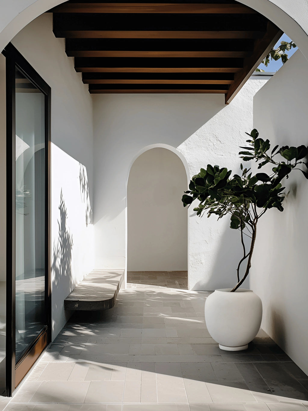 101 CPH Sunao Planter, a large cream-white earthenware planter with a subtle textured finish and rounded shape, holding a leafy plant in a sunlit architectural space. A premium design accent for elegant interiors.