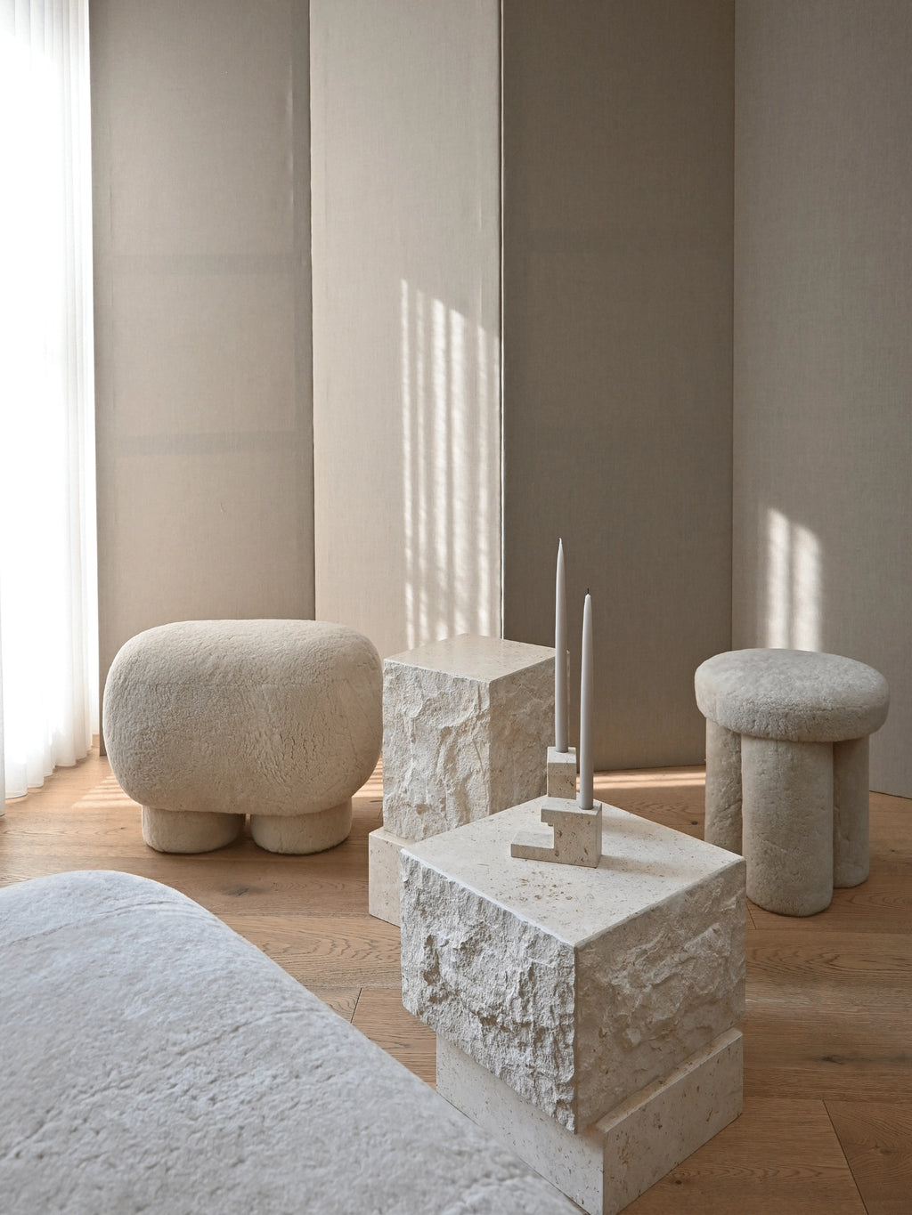 101 CPH Temple Coffee Table Set: two raw, light beige travertine block coffee tables with organic texture, styled with matching candles and bouclé ottomans on a wooden floor, creating a luxury modern living room arrangement.