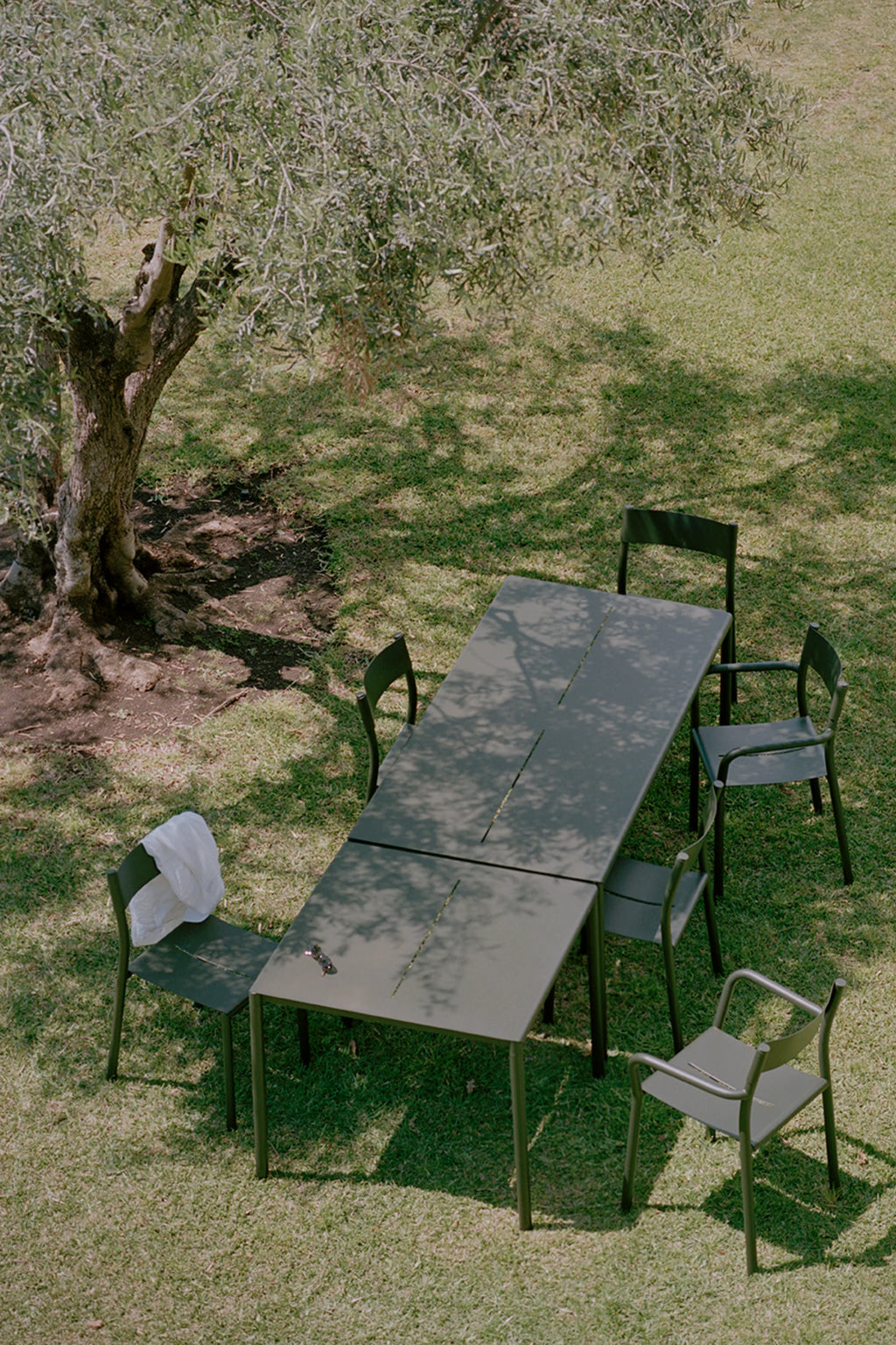 New Works Outdoor May Furniture Set for 4 Persons, a modern minimalist outdoor dining set featuring a rectangular dark olive green metal table composed of two panels, each with a slender central slot, paired with matching matte.