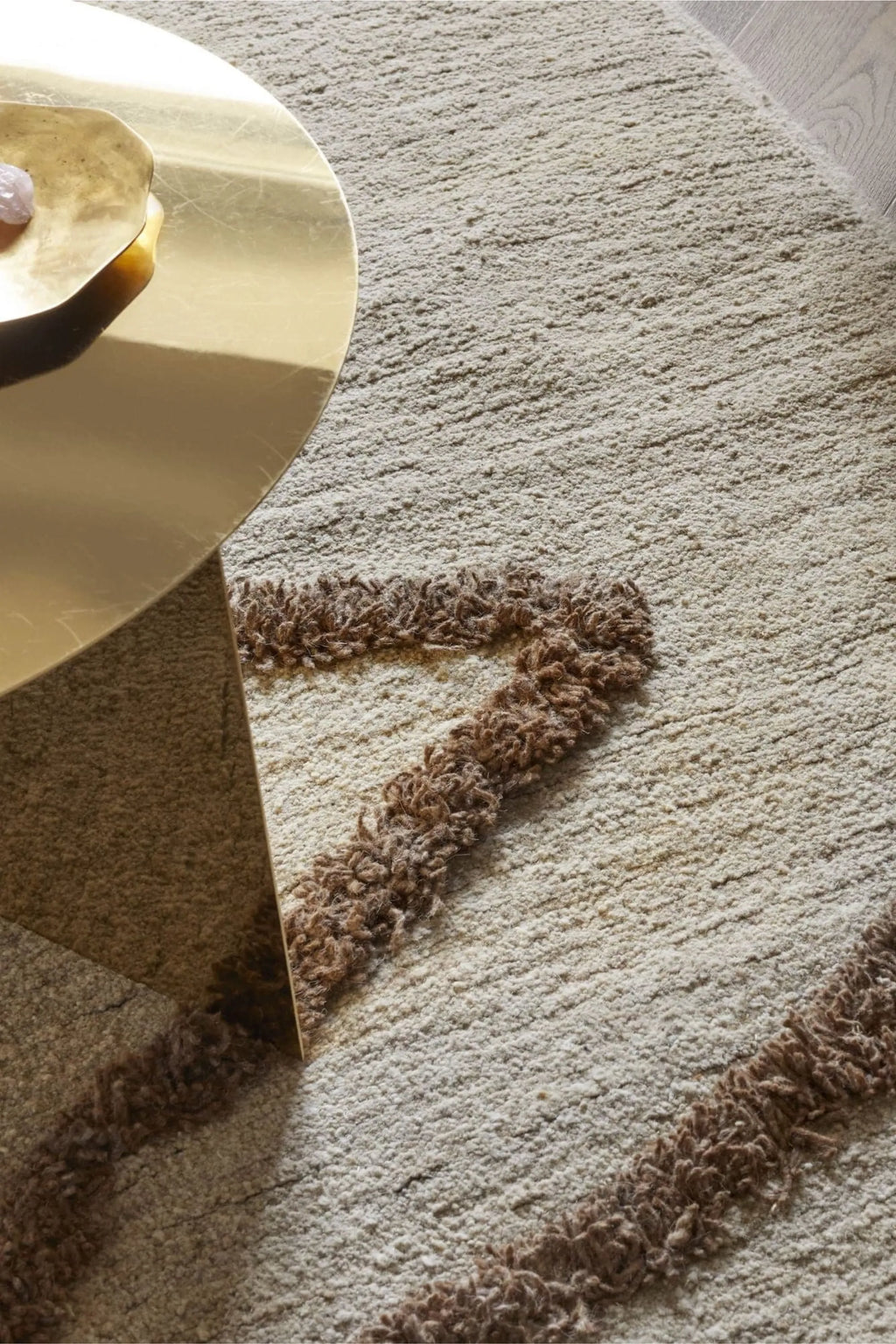 Sera Helsinki Vuoristo Rug, a luxurious hand-knotted wool area rug featuring a plush, high-pile cream-colored base with a contrasting abstract geometric pattern in rich brown, showcasing natural, undyed wool tones and a shaggy texture. This organic modern rug is perfect for adding warmth and Scandinavian style to minimalist living rooms, cozy bedrooms, or boho-inspired spaces.