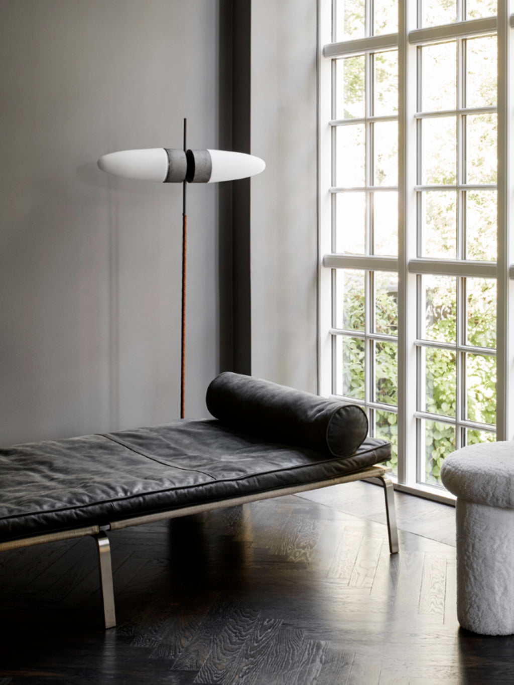 101 CPH Bull Floor Lamp in a modern living room, featuring a white opal glass shade with a concrete-effect band on a slender dark metal and bronze-toned pole. This luxury, minimalist lighting fixture illuminates a chic space.