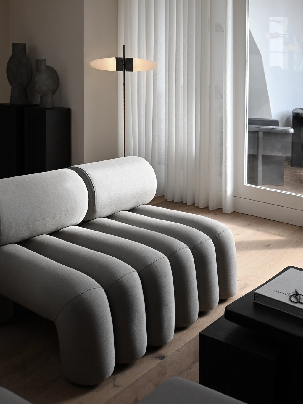 101 CPH Bull Floor Lamp in a modern living room setting, featuring a sleek black metal stem, oval frosted white glass disc diffuser, and warm glow. A luxury design for sophisticated lighting.