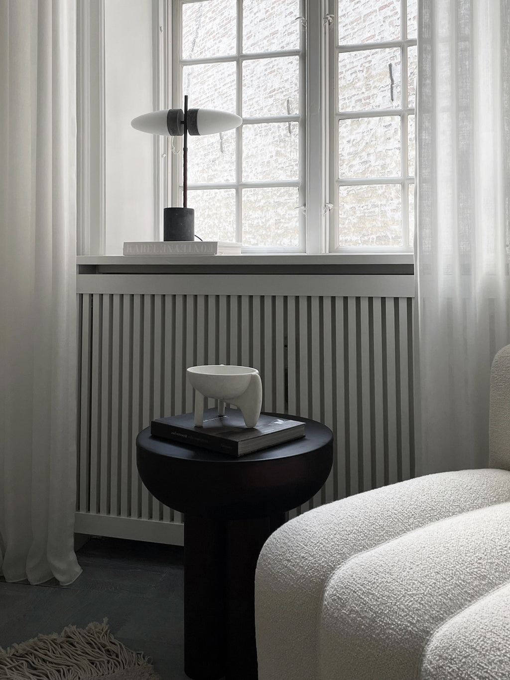 101 CPH Bull Table Lamp features a dark gray stone base, slim black pole, and two elongated frosted white glass shades, styled on a window sill for modern illumination.