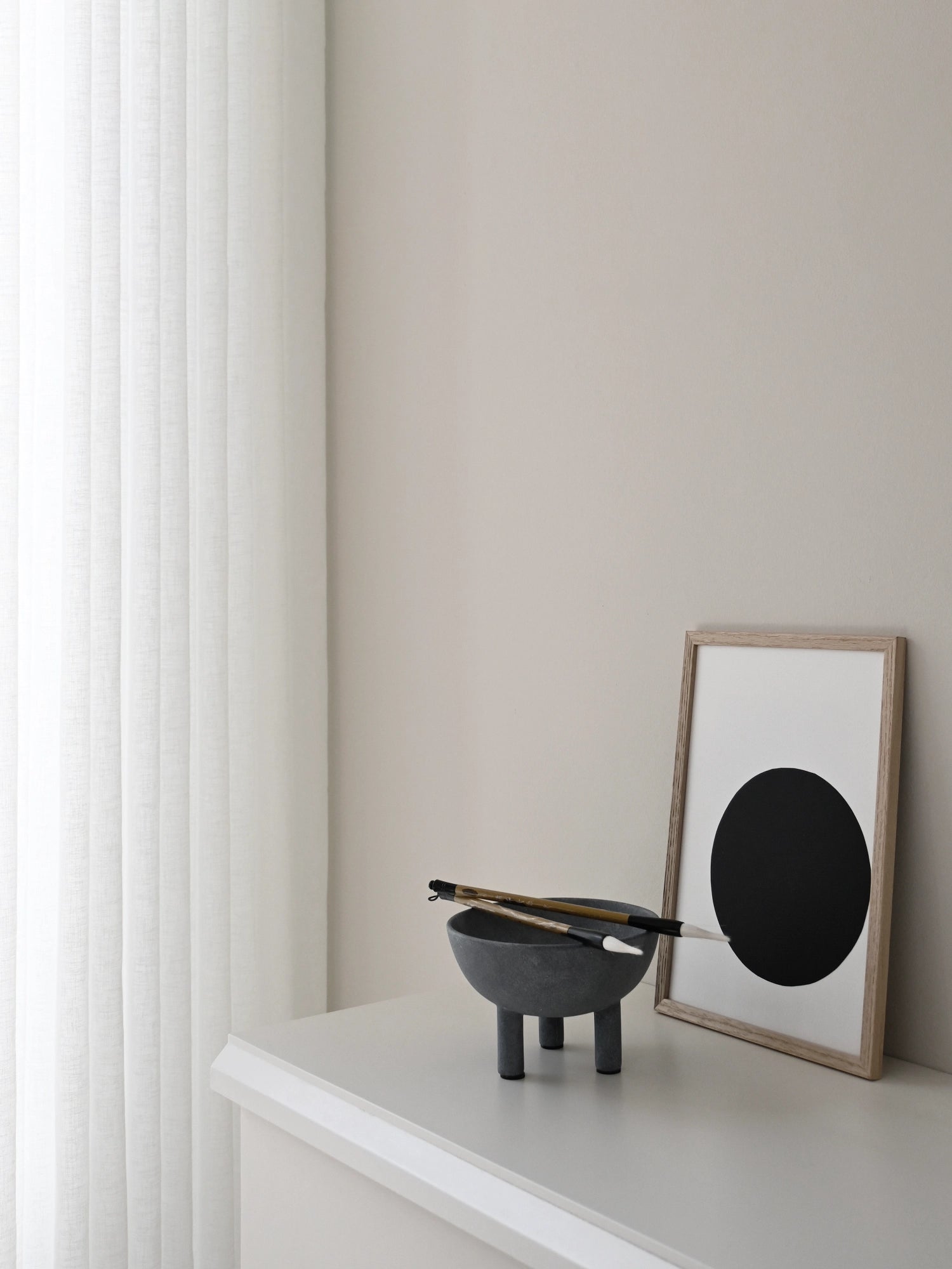 101 CPH Duck Bowl, a unique dark grey speckled stoneware bowl with three sturdy legs, displayed on a white shelf with paintbrushes. A luxury design piece for modern interiors.
