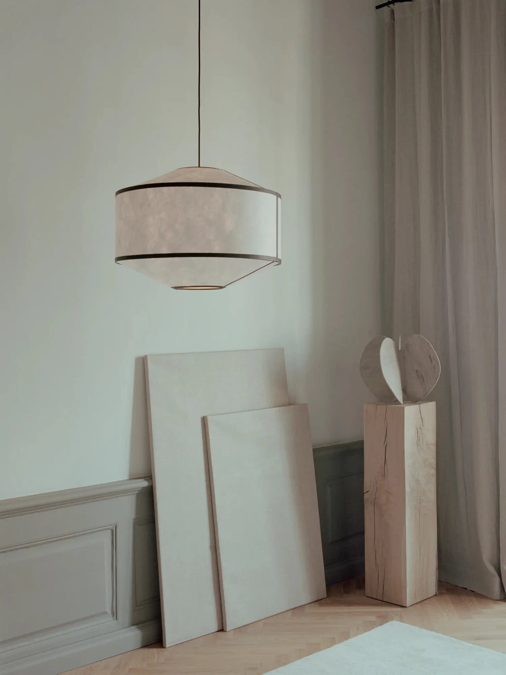 New Works Kite Pendant Lamp featuring an off-white rice paper shade with black trim, suspended in a minimalist room with natural light. A premium, modern lighting fixture for contemporary interiors.