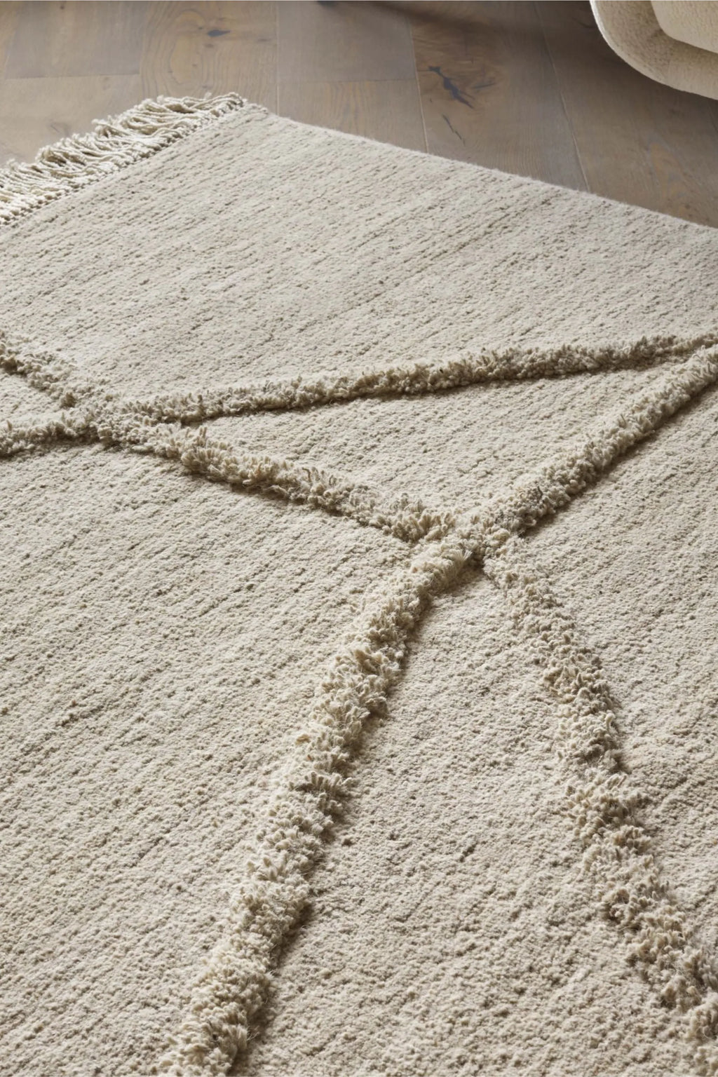 Sera Helsinki Vuoristo Rug, a natural undyed wool area rug in a light cream and beige color palette, featuring a plush shaggy pile texture with distinctive raised geometric lines and fringed edges. This Scandinavian-inspired rug is perfect for adding warmth and organic texture to boho living rooms, minimalist bedrooms, or cozy contemporary spaces.