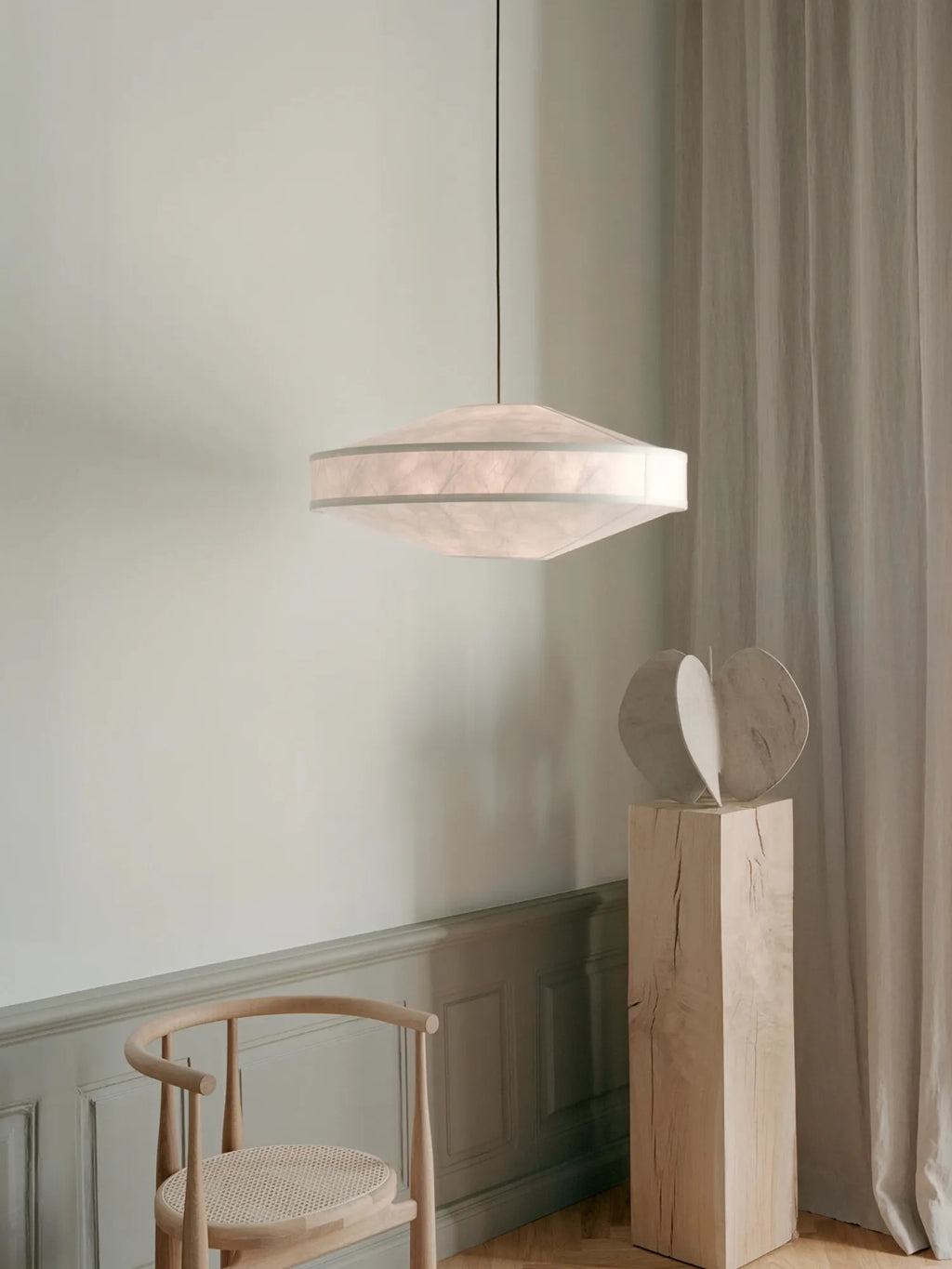 New Works Kite Pendant Lamp, a modern, saucer-shaped ceiling light with a delicate, translucent white paper shade and fine white ribs, hanging in a minimalist interior. Perfect for creating ambient lighting.