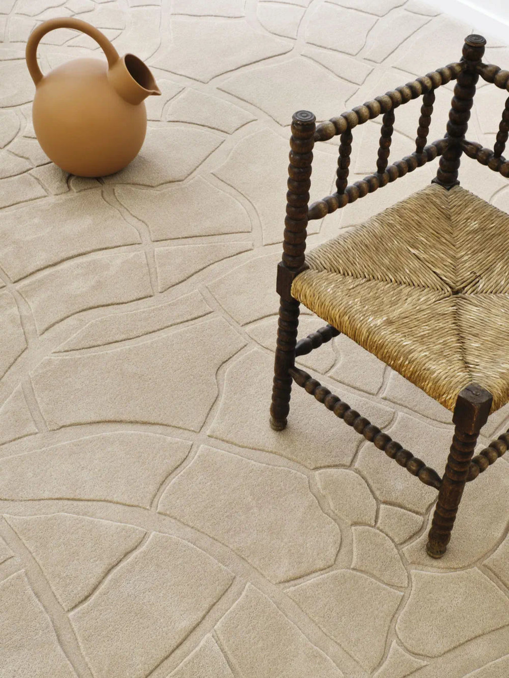 alp_ Aride I Rug, a neutral light beige area rug with a distinctive abstract carved pattern, evoking natural flagstones or organic cracked earth. This plush cream-colored textured rug features a soft, high-low pile that creates subtle depth and a luxurious feel, perfect for organic modern or contemporary living rooms, minimalist bedrooms, or rustic Mediterranean interiors.