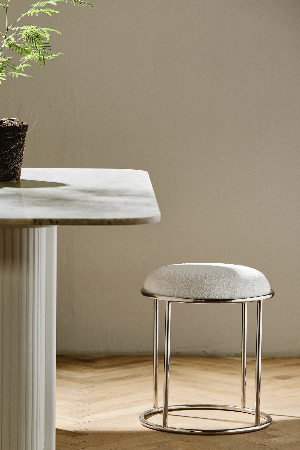 Nordal Komati Stool, a modern minimalist accent stool featuring a plush, round cream bouclé upholstered seat set atop a sleek polished chrome metal frame with slender vertical legs and a circular base. Ideal as a contemporary vanity stool, bedroom accent, or stylish seating for living rooms and entryways.
