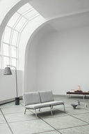 Modern gray sofa in a minimalistic room with large windows.