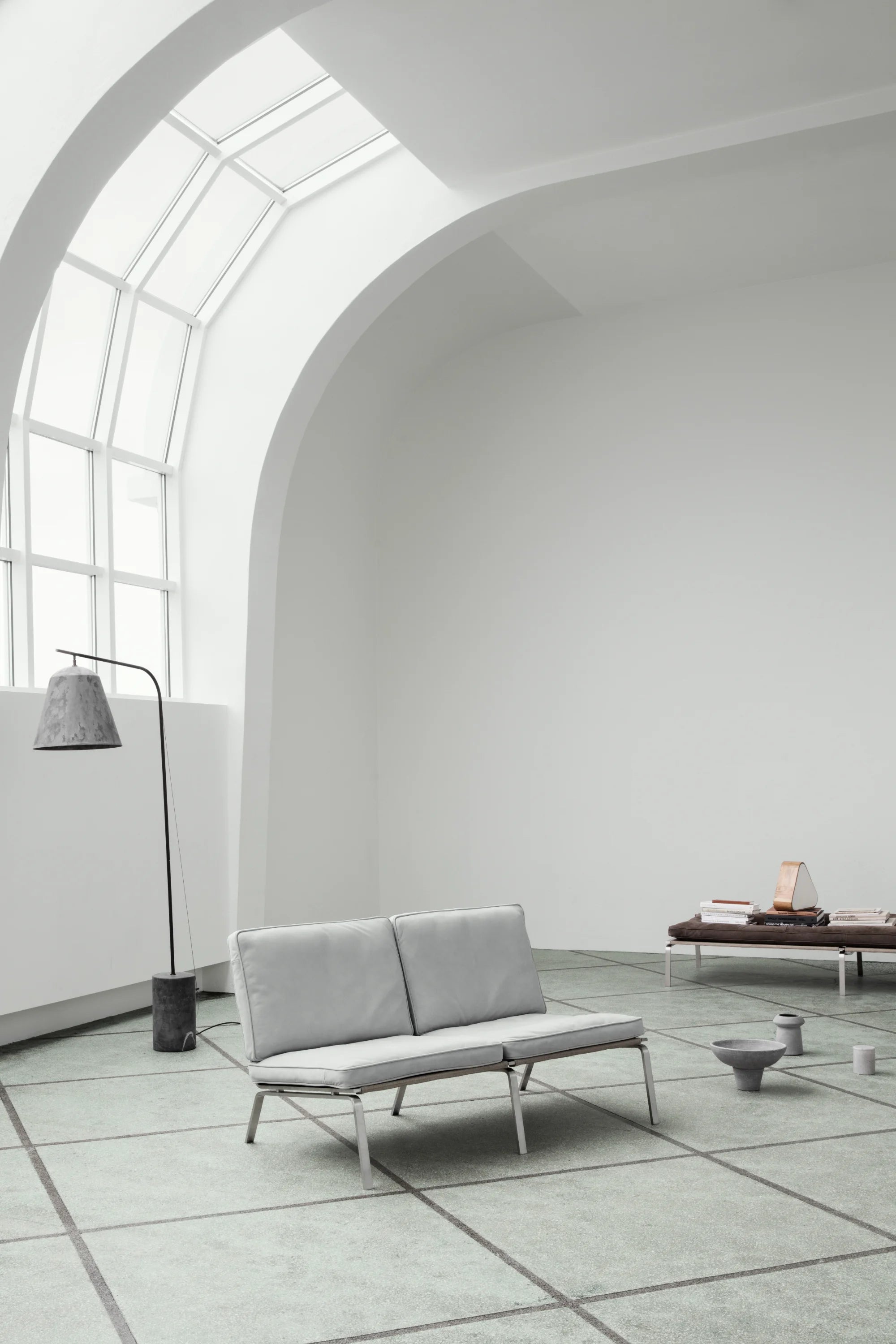 Modern gray sofa in a minimalistic room with large windows.
