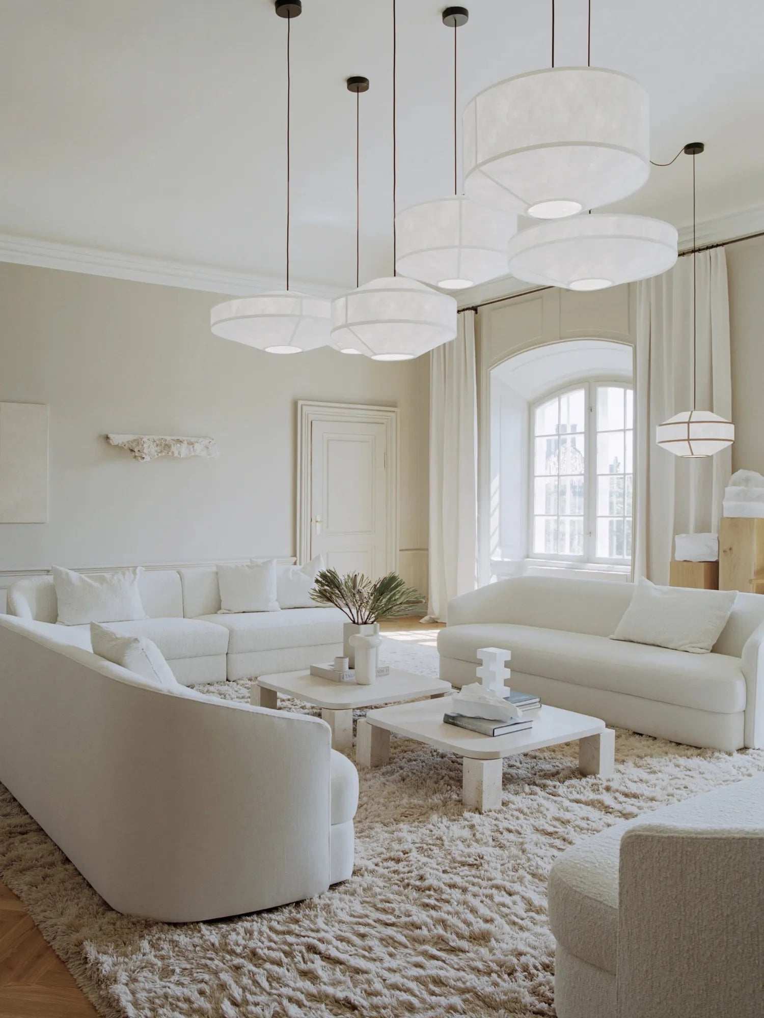 New Works Kite Pendant Lamp in various sizes, featuring elegant white fabric shades with visible structural lines, suspended from black ceiling mounts in a luxurious all-white living room setting. Ideal for sophisticated interior lighting.