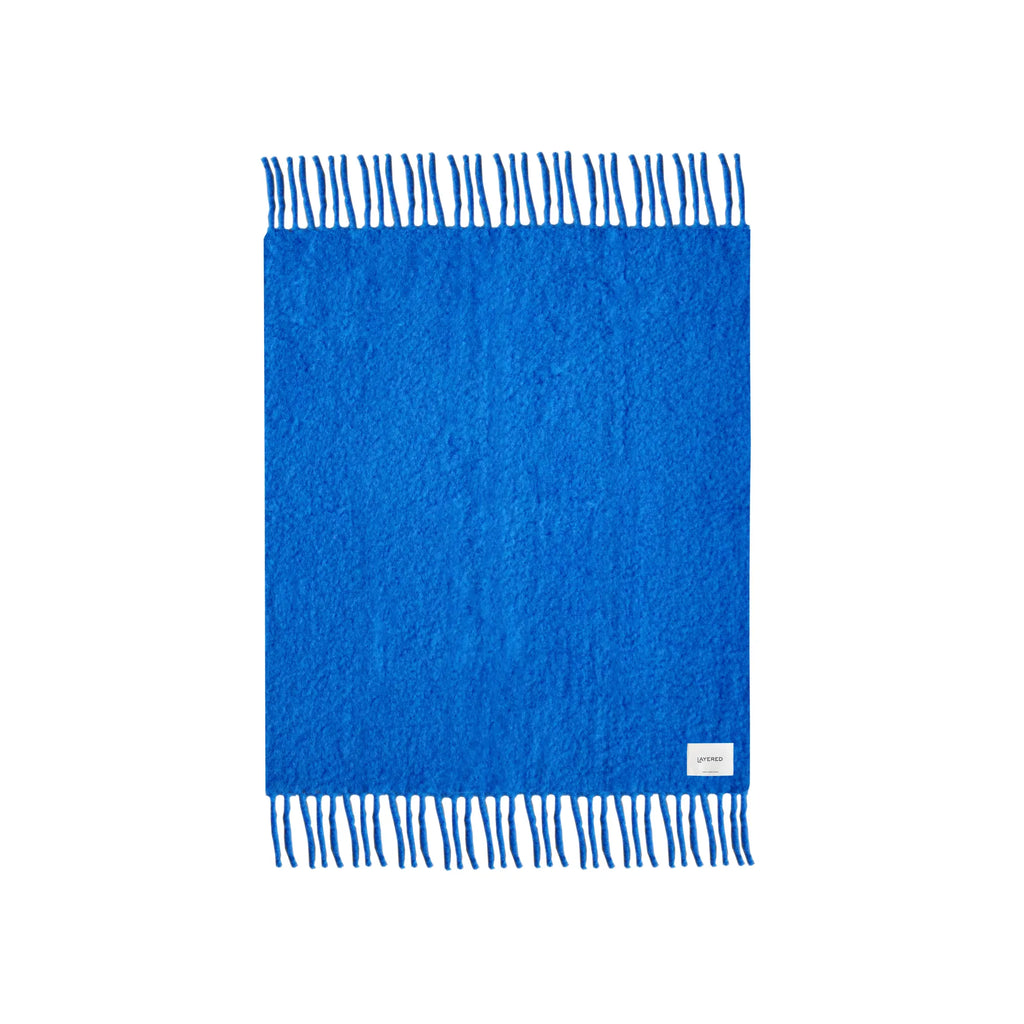 Chunky mohair blanket in dark charcoal color on a bed