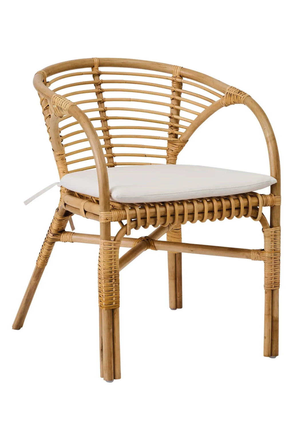 Tine K Dola Rattan Chair - Set of 2, a natural rattan dining chair featuring a gracefully curved backrest and armrests, with a slatted design and intricate hand-woven rattan detailing throughout its sturdy frame. It includes a plush white fabric seat cushion for comfort. This coastal-inspired boho chair is ideal for a relaxed dining room, covered patio seating, or as a charming organic modern accent in a living space.