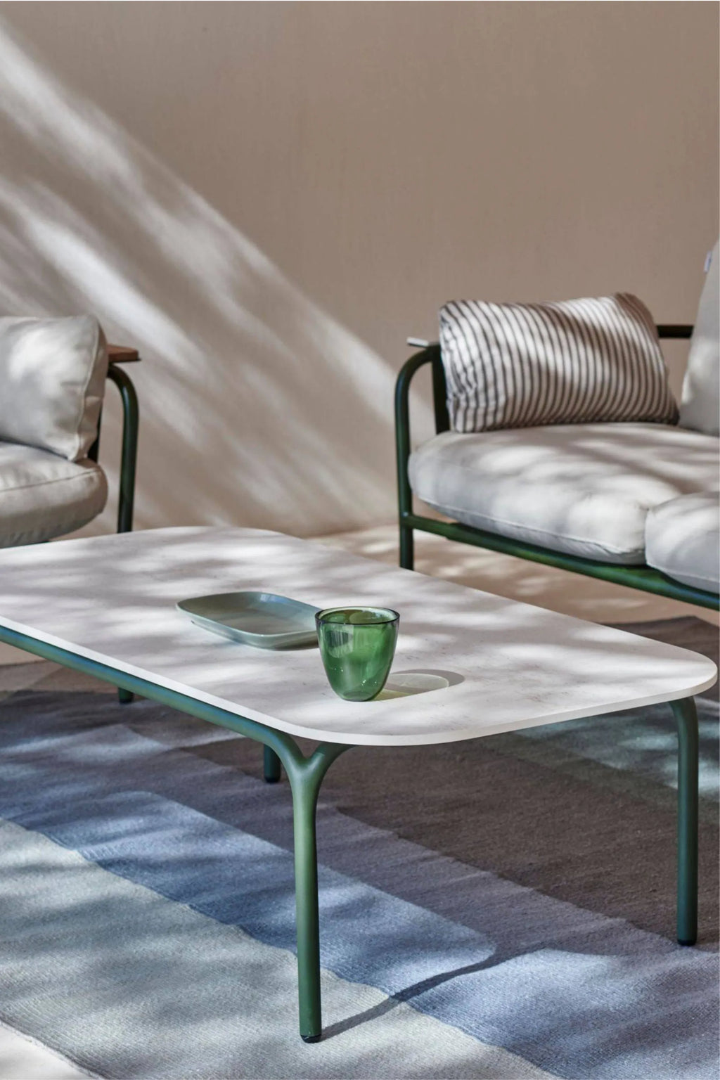 Gandia Blasco Capa Coffee Table, a modern minimalist outdoor coffee table featuring a light grey textured Dekton tabletop with softly rounded corners and a sturdy matte dark green aluminum frame. Its unique Y-shaped legs provide a contemporary aesthetic, making it perfect for stylish outdoor living rooms, patios, or garden lounge areas.