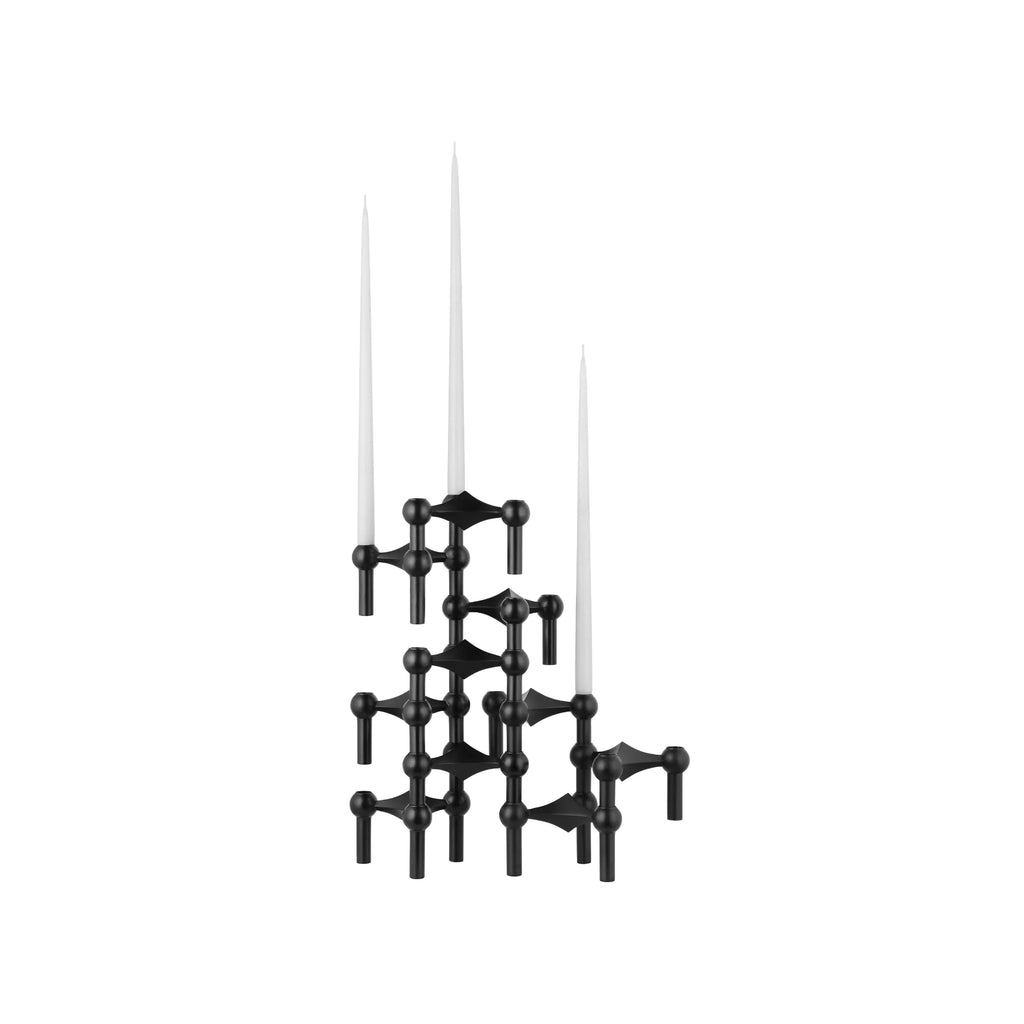 Stoff Nagel Modular Candle Holder - Black - Configuration 6, a striking mid-century modern matte black metal candle holder featuring an interlocking geometric design of spheres and prongs, configured into a sculptural tower holding three white taper candles. This brutalist-inspired piece is perfect as a contemporary dining table centerpiece or a minimalist accent for living room shelf styling.