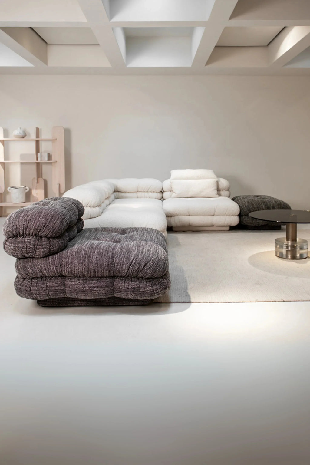 Hessentia Lowell Modular Sofa, a contemporary organic modern sectional featuring plush, deeply cushioned bouclé fabric in a soft cream color, combined with a contrasting dark grey textured fabric on the armrest and ottoman modules. This low-profile cloud sofa design offers ultimate comfort and versatile configuration for a cozy minimalist living room or spacious lounge area.
