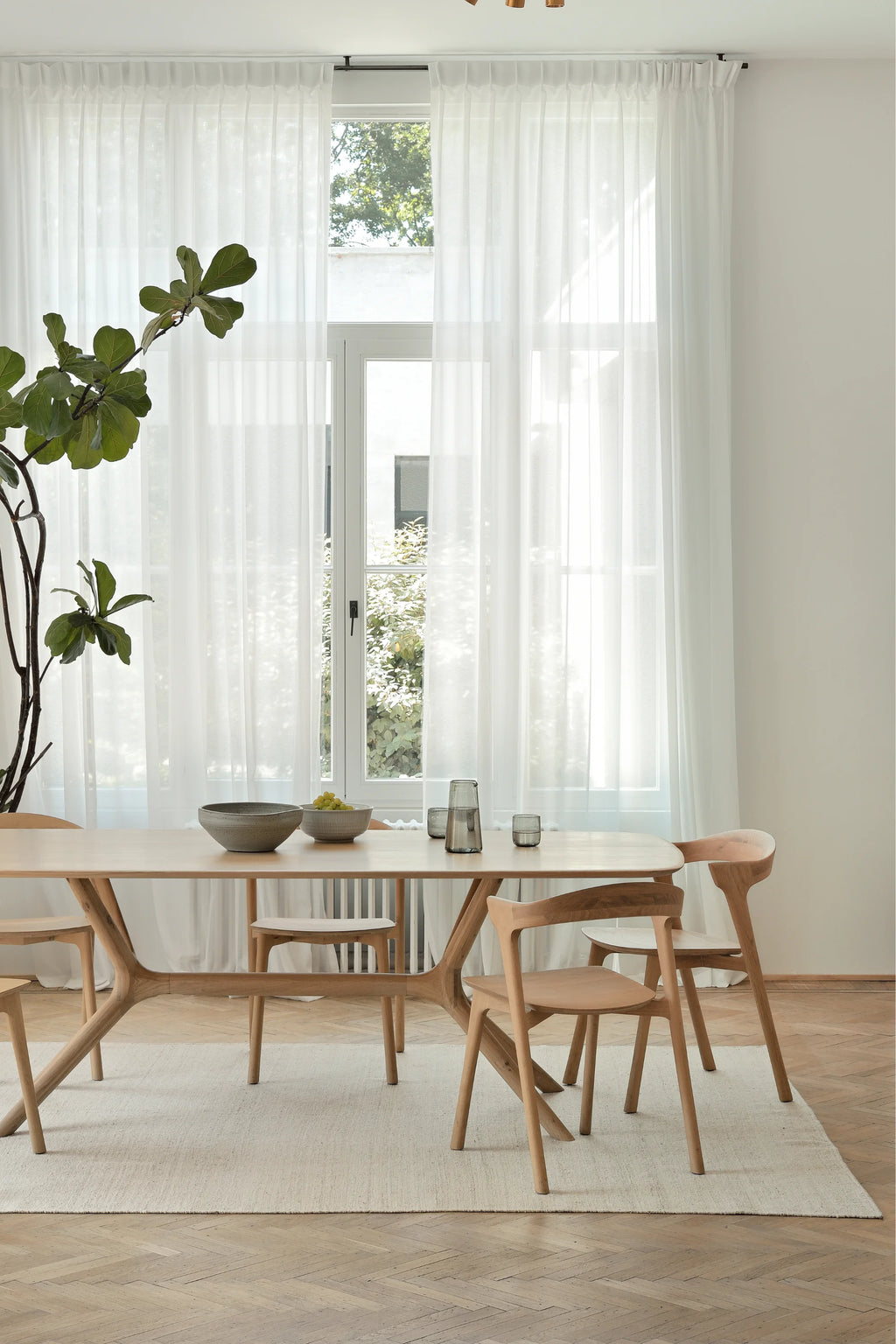 Ethnicraft X Dining Table, a modern solid oak dining table featuring a light natural wood finish and a distinctive sculptural X-shaped base. Its sleek rectangular tabletop has softly rounded corners, showcasing the beautiful, smooth grain of the natural oak wood. Perfect for contemporary dining rooms, minimalist kitchens, or Scandinavian-inspired living spaces.