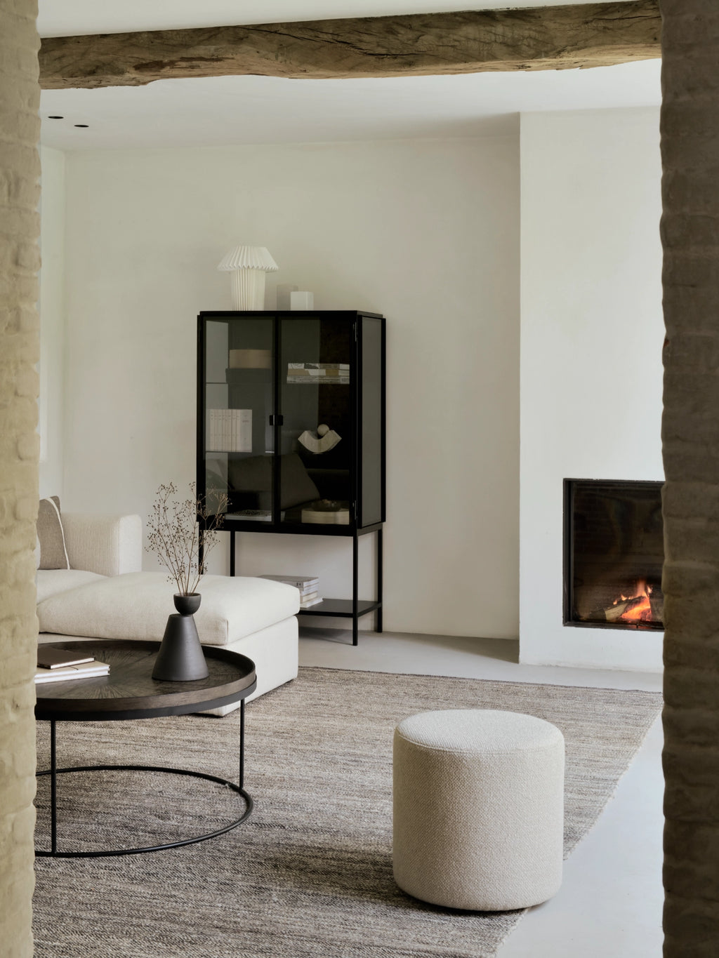 Ethnicraft Barrow Pouf, a cylindrical modern minimalist pouf upholstered in a textured cream bouclé fabric with a soft, inviting weave and organic appeal. This versatile round ottoman is perfect as accent seating or a comfortable footrest for Scandinavian living rooms or organic modern bedrooms.