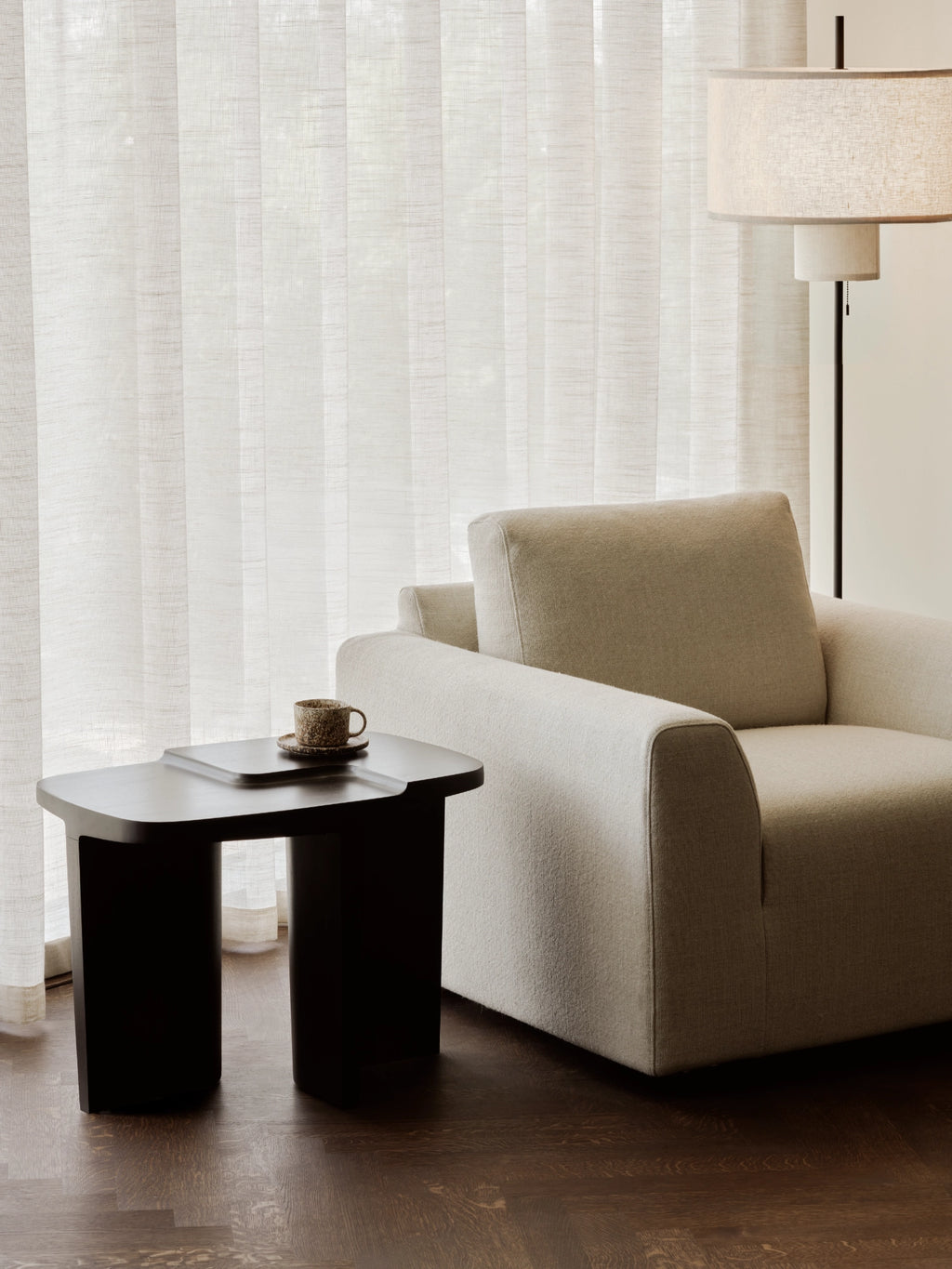 Ethnicraft Brutalist Side Table, a sculptural solid dark wood side table with a robust, minimalist form and a smooth matte finish, featuring a distinctive tiered rectangular top and two thick, curved legs.