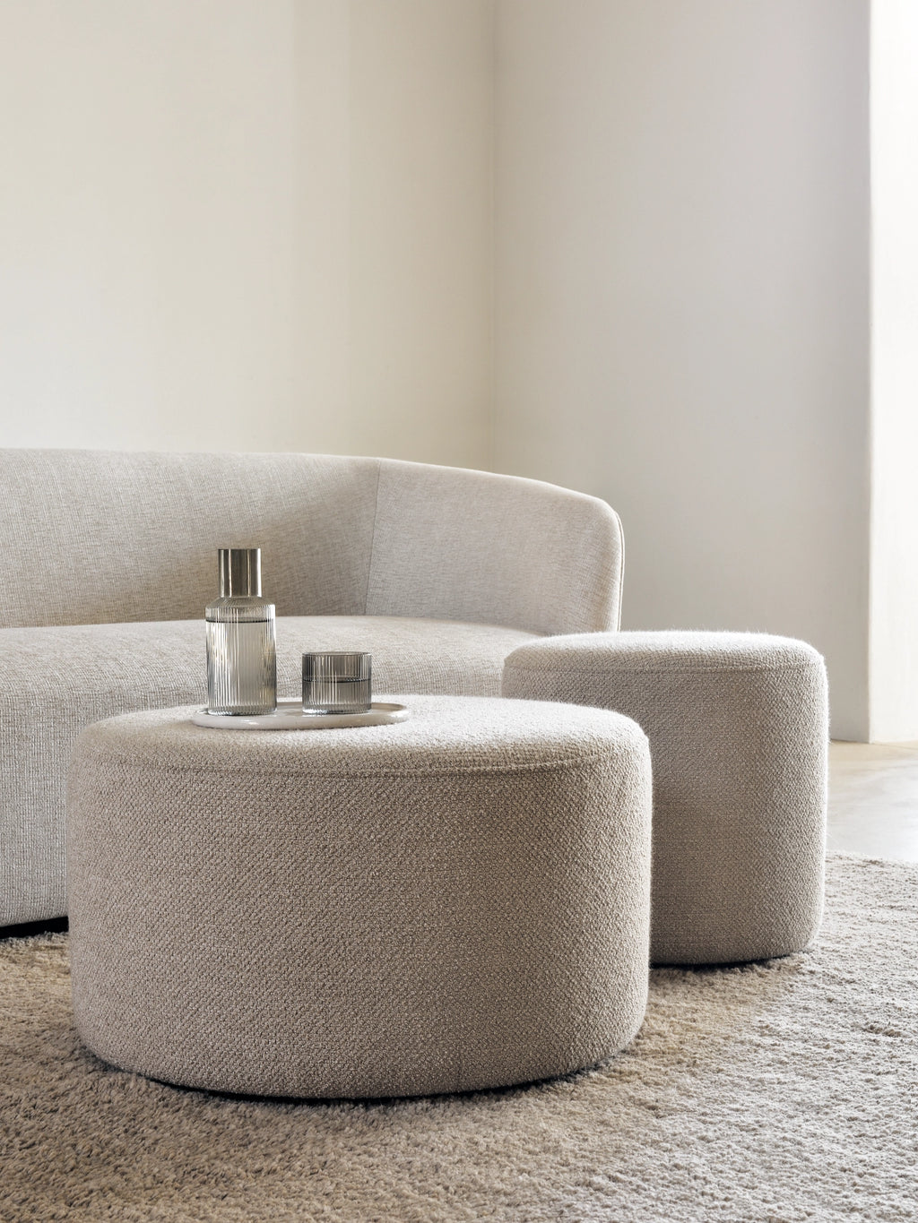 Ethnicraft Barrow Pouf, a modern minimalist accent pouf upholstered in a warm light beige, textured bouclé-like fabric with a soft, inviting weave.