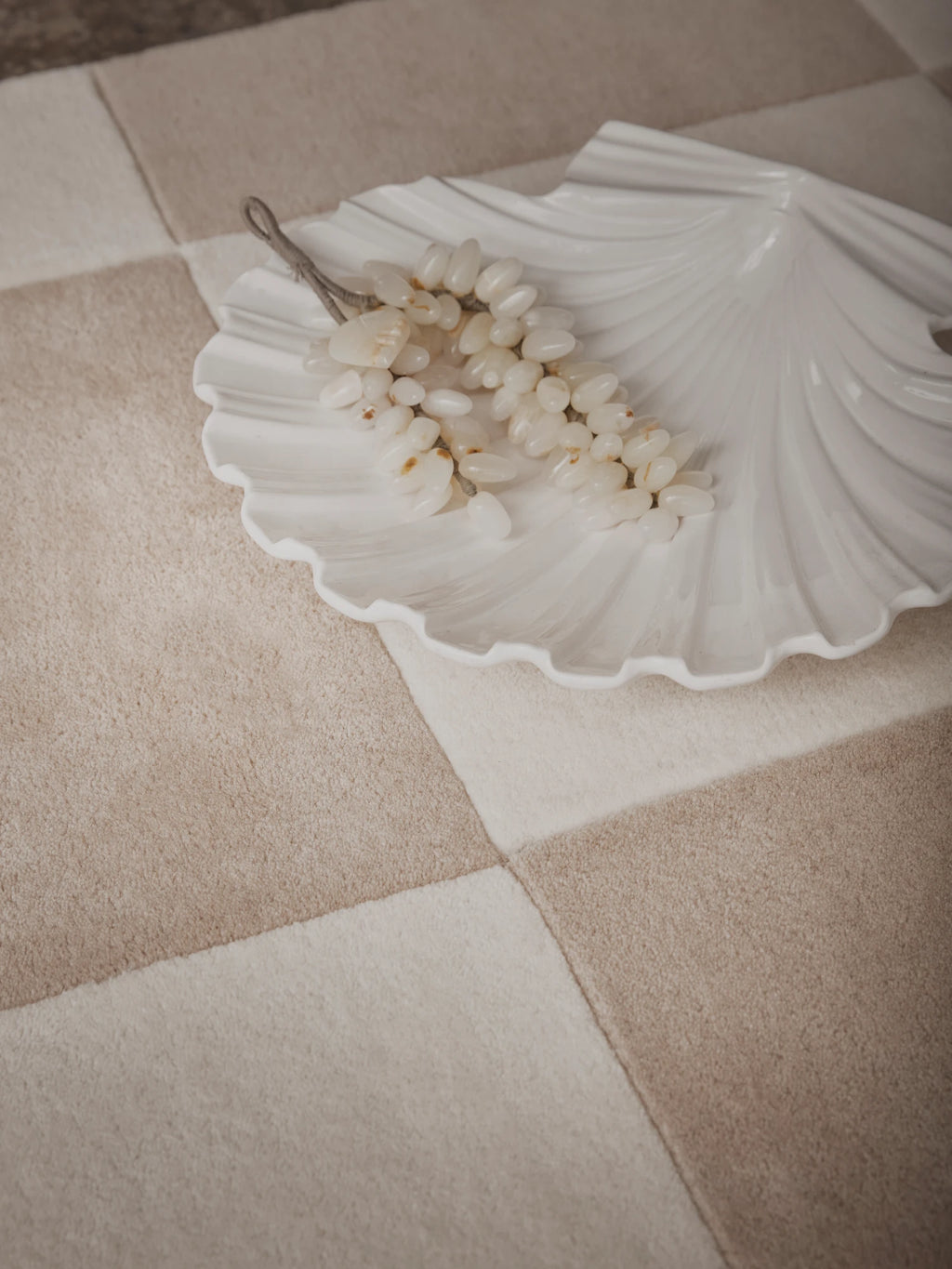 Tinted Objects Hafstrom Wool Rug, featuring a soft, plush texture with a checkerboard pattern in varying shades of light beige and warm taupe. This luxurious wool rug is perfect for adding warmth and sophisticated style to a living room or bedroom for those seeking modern, organic home decor.