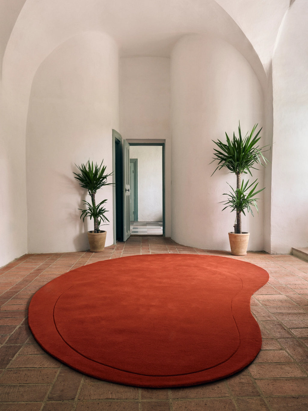 Layered Residue Wool Rug, a striking organic modern rug featuring an irregular freeform shape in a rich terracotta orange hue with a subtle border detail. This plush, hand-tufted wool area rug offers a soft texture and a sculptural presence, ideal for adding warmth and artistic flair. Perfect for contemporary living rooms, Mediterranean-inspired entryways, or as a unique designer rug for a bedroom accent.