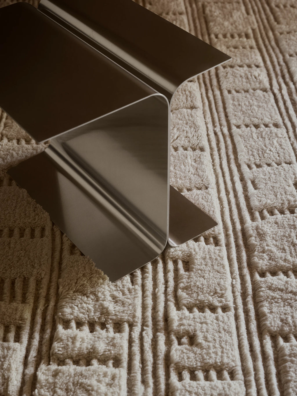 Tinted Objects Lydahl Handknotted Rug, featuring a textured cream or off-white wool pile with raised stripes and geometric patterns. This luxurious area rug adds warmth and modern style to any living room or bedroom.
